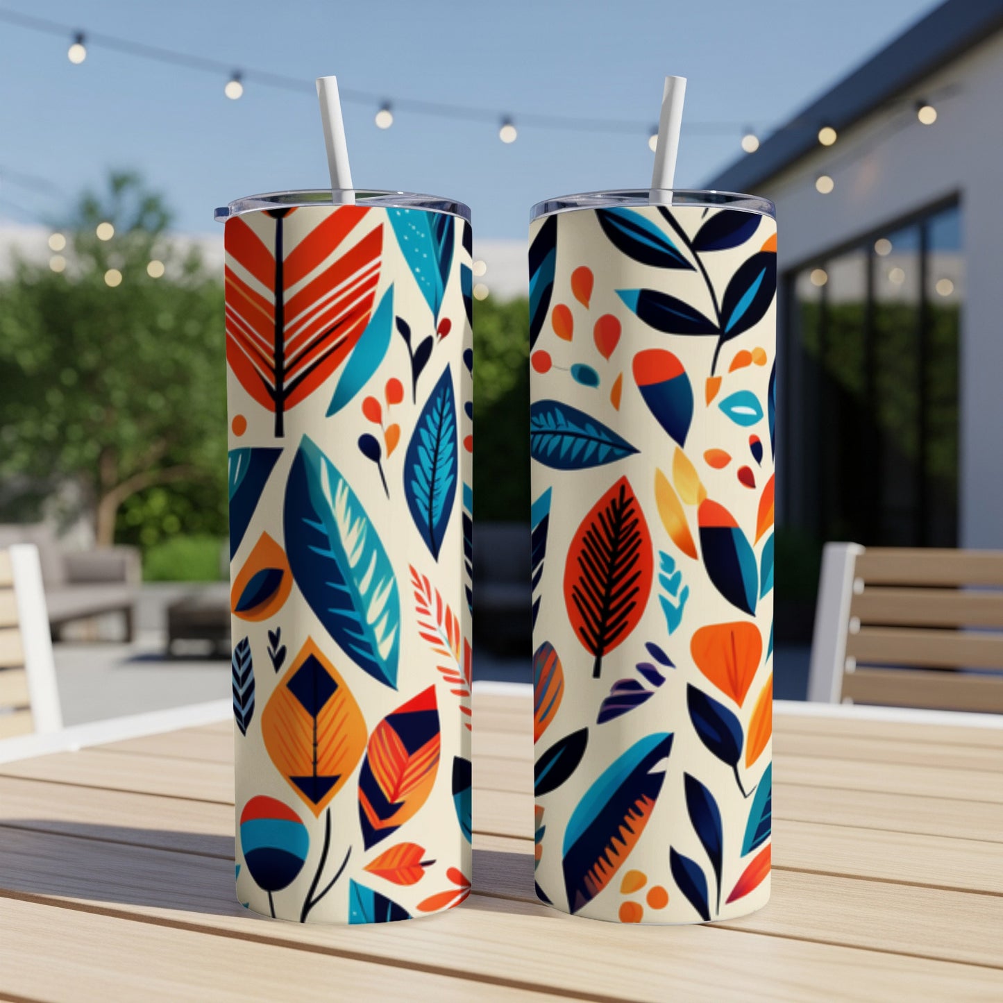 Two cream-colored tumblers with a colorful abstract leaf pattern and white straws.