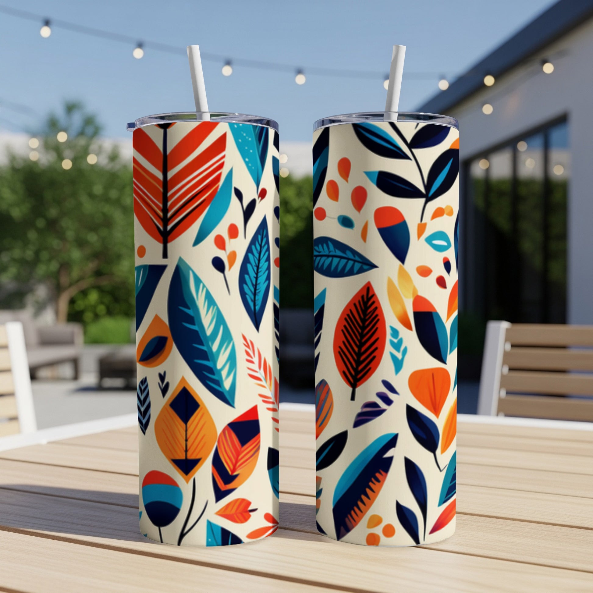Two cream-colored tumblers with a colorful abstract leaf pattern and white straws.