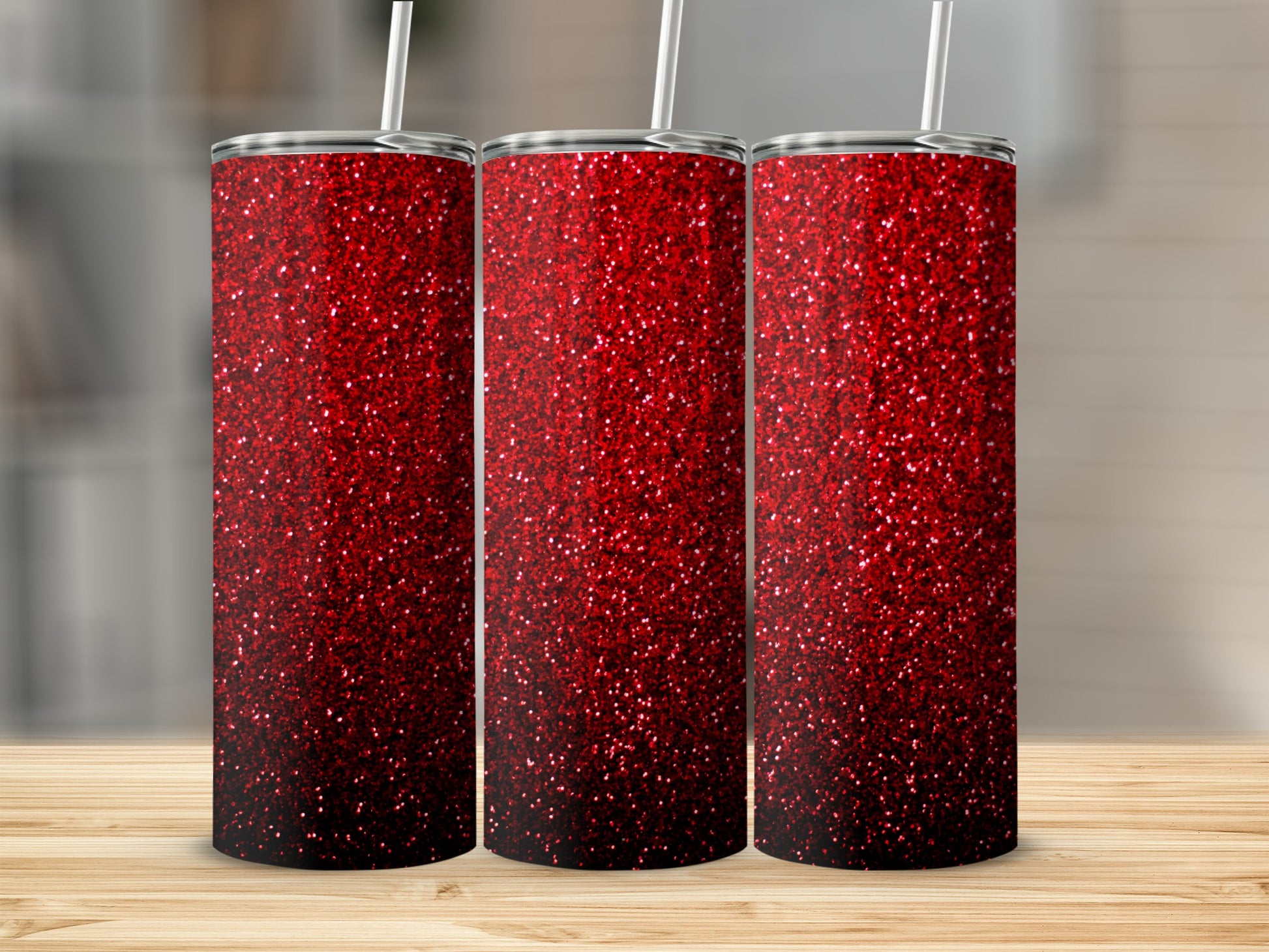 Three red glitter tumblers with straws on a wooden surface.