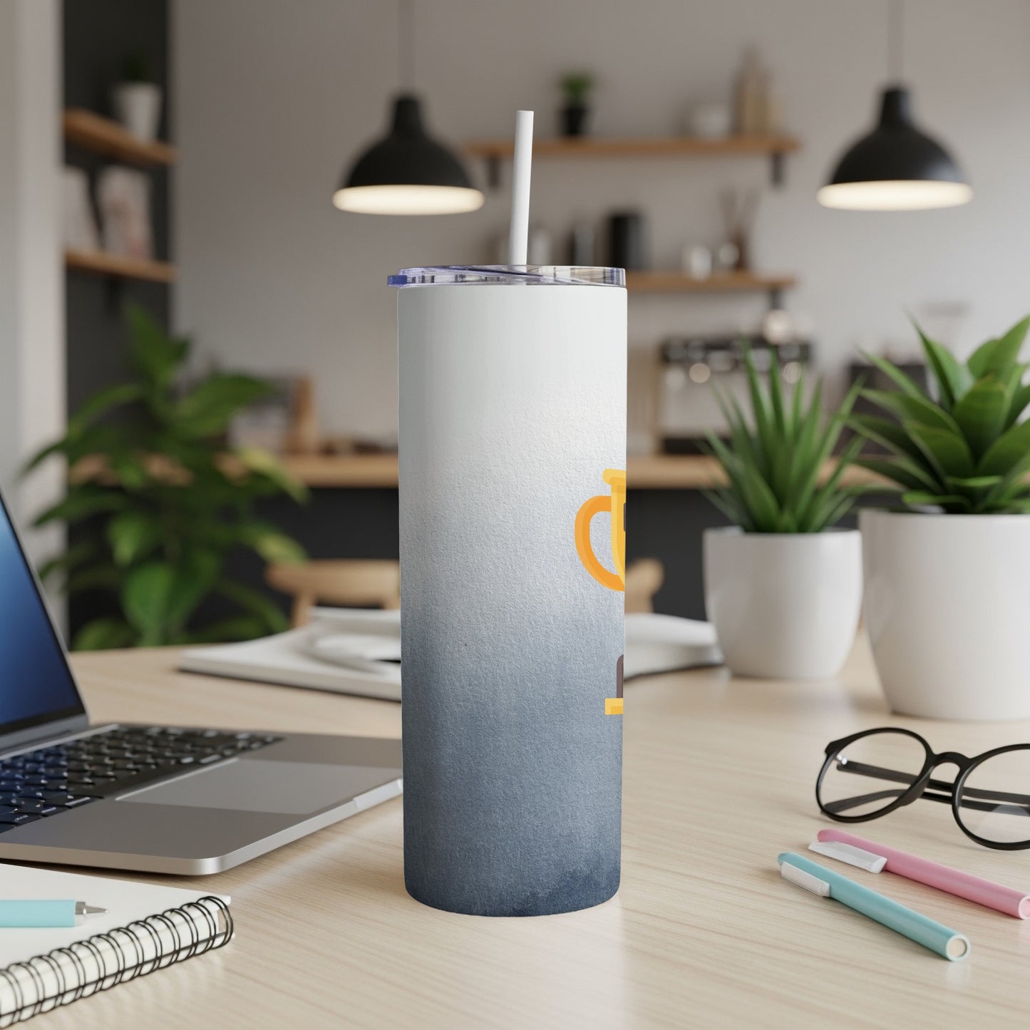 Gradient tumbler with orange text on a desk next to a laptop.