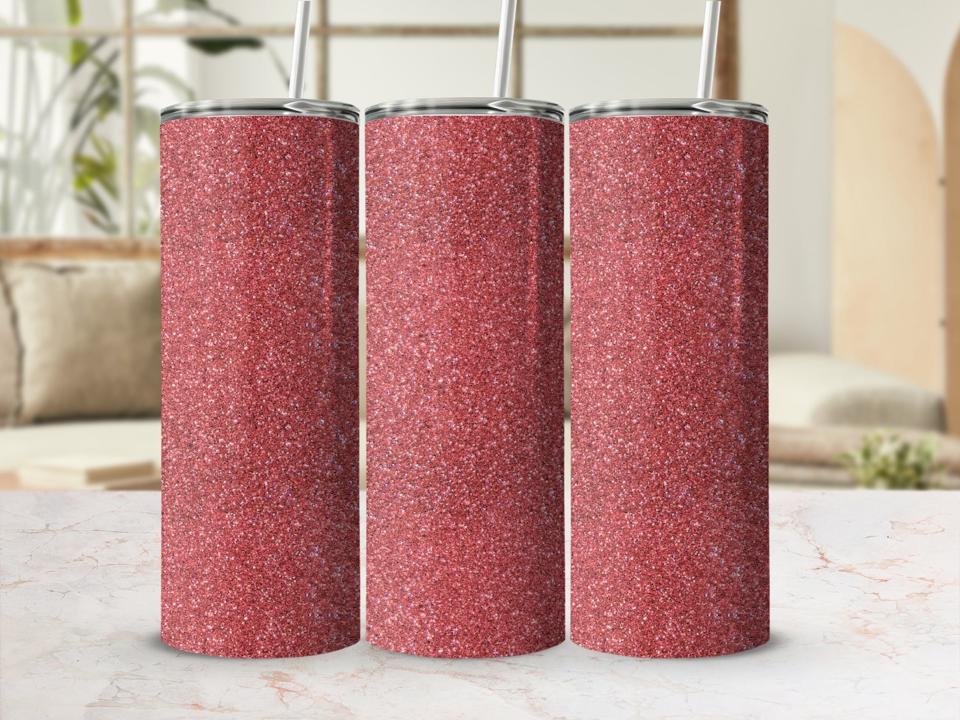 Three red glitter tumblers with silver lids and straws on a marble surface.