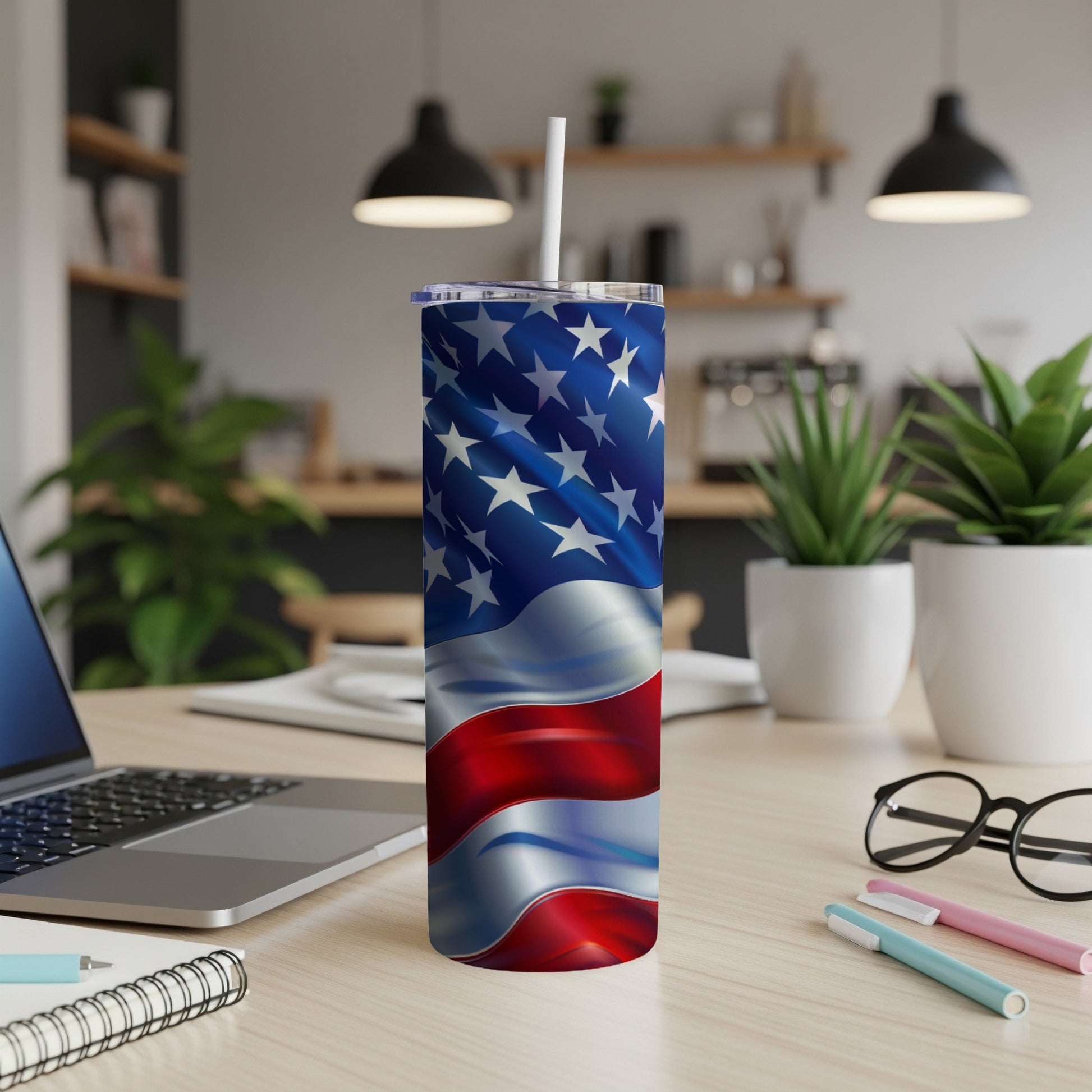 Waving American flag tumbler with a white straw on a desk.