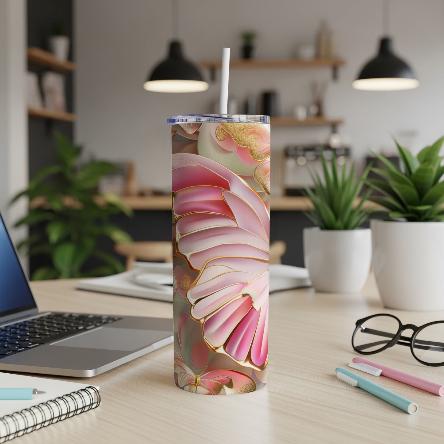 Floral patterned tumbler with pink and gold accents on a desk.