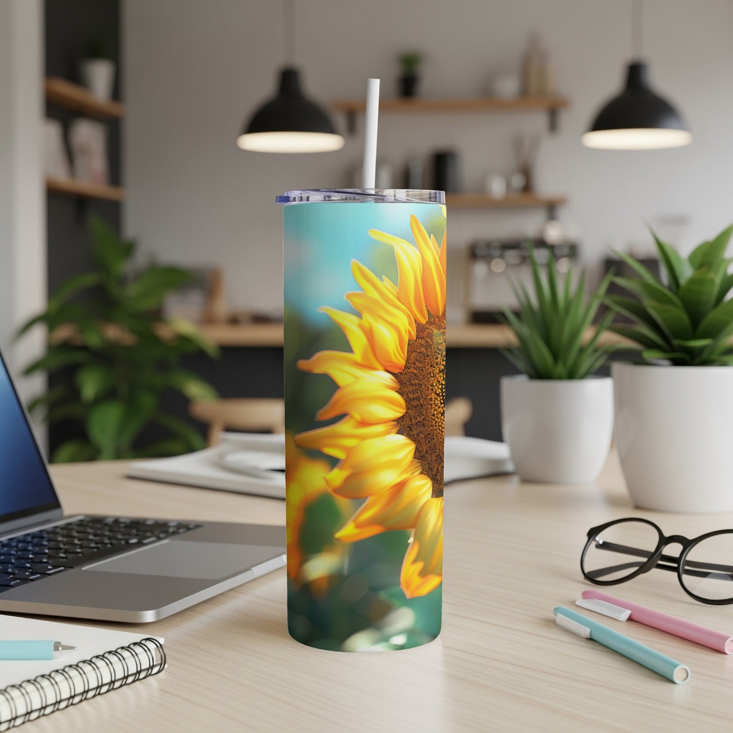Sunflower on a tumbler with a straw, on a desk.