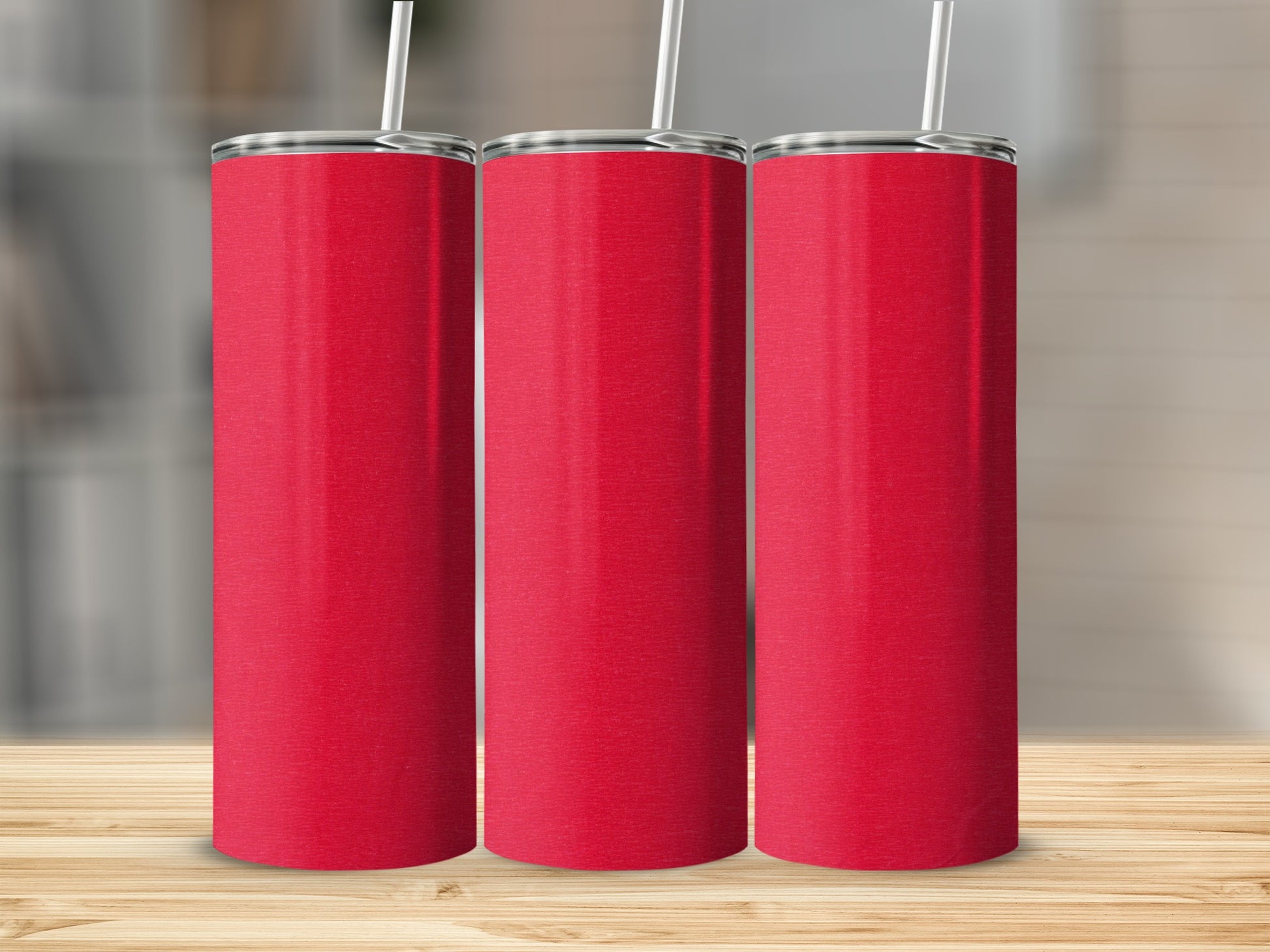 Three red tumblers with white straws on a wooden surface.