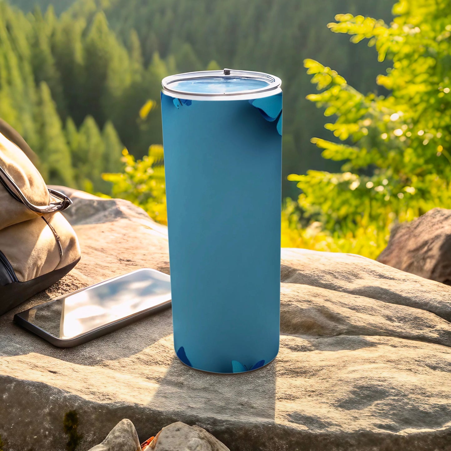 Blue speckled tumbler next to a phone and backpack outdoors.