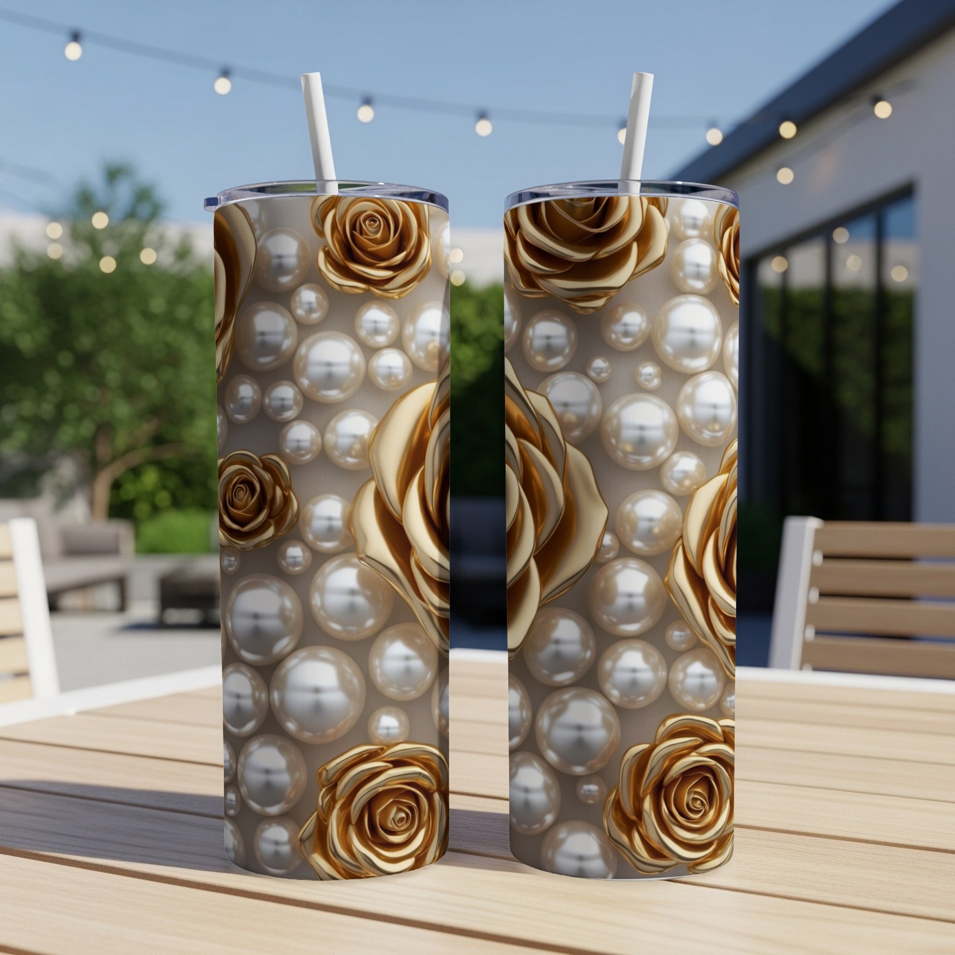 Two gold rose and pearl patterned tumblers on a wooden table outdoors.