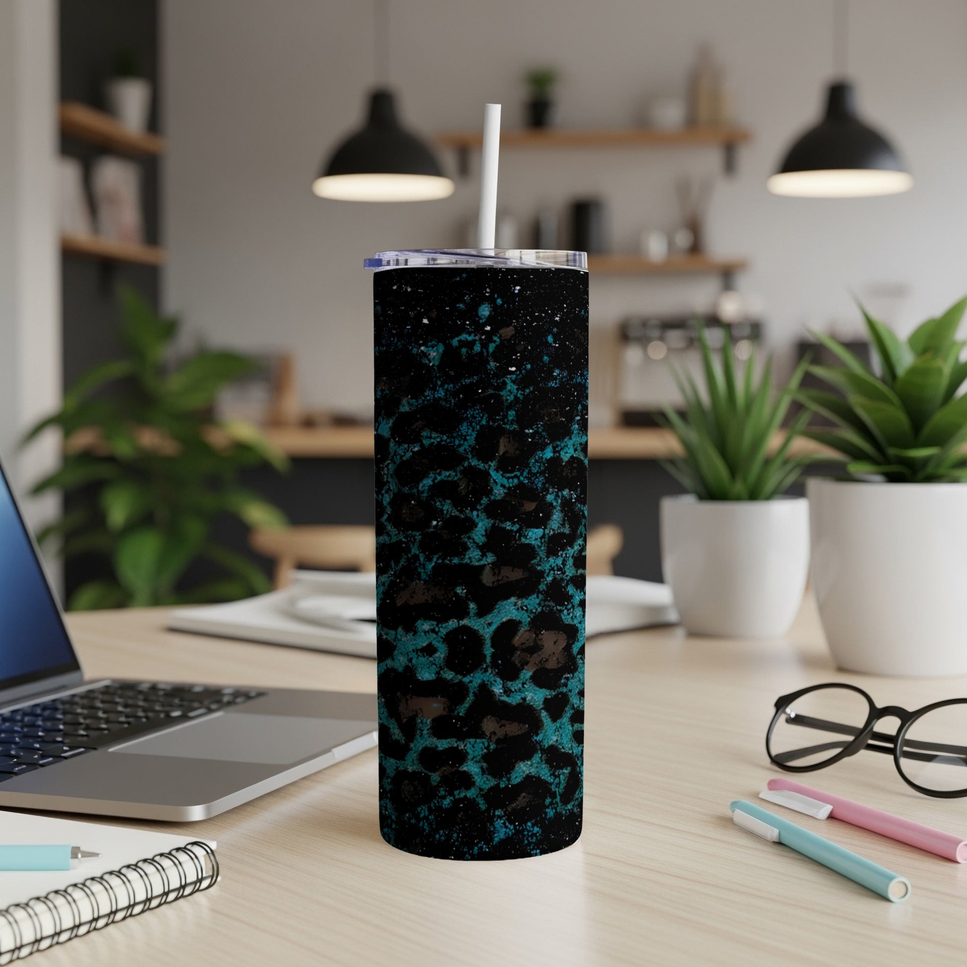 Black tumbler with teal leopard print, white straw, on a desk.