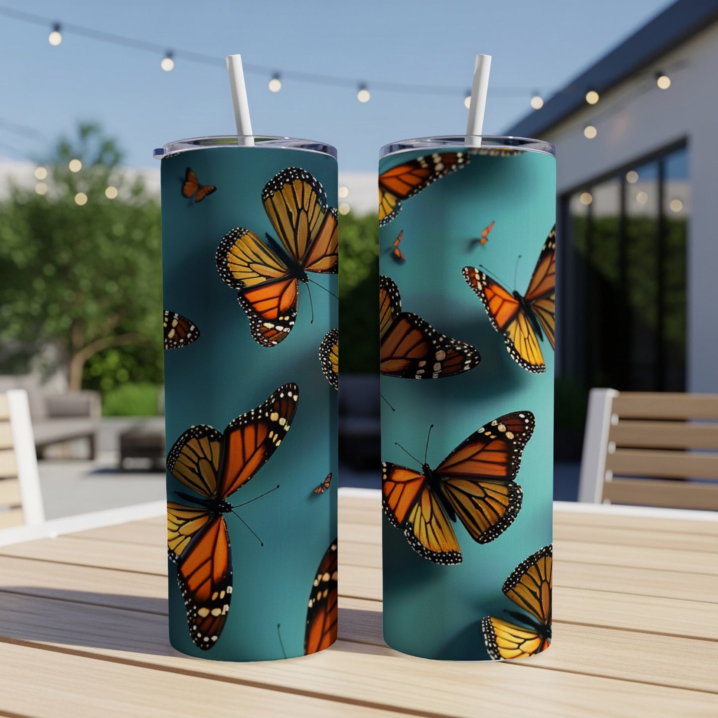 Two tumblers with monarch butterfly pattern on a patio table.