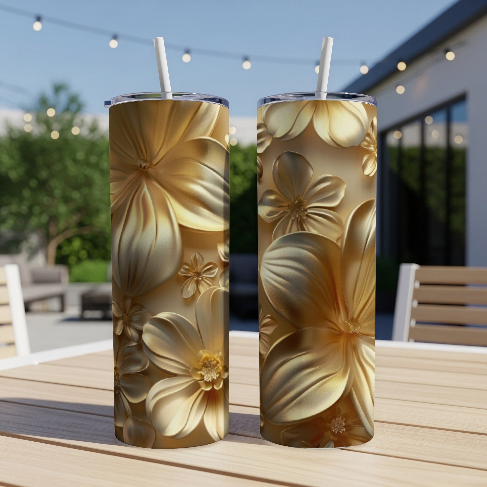 Two gold floral patterned tumblers on a wooden table outdoors.