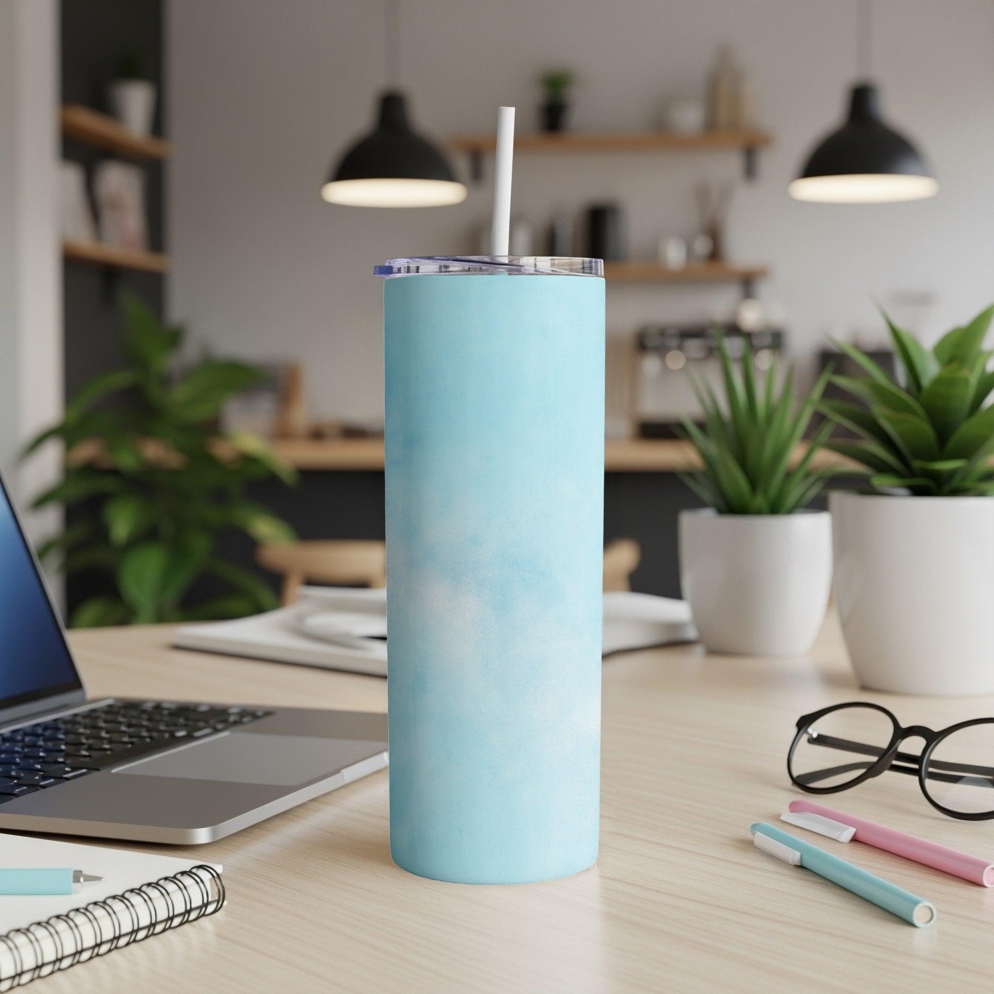 Light blue tumbler with a cloud pattern on a desk with a laptop.