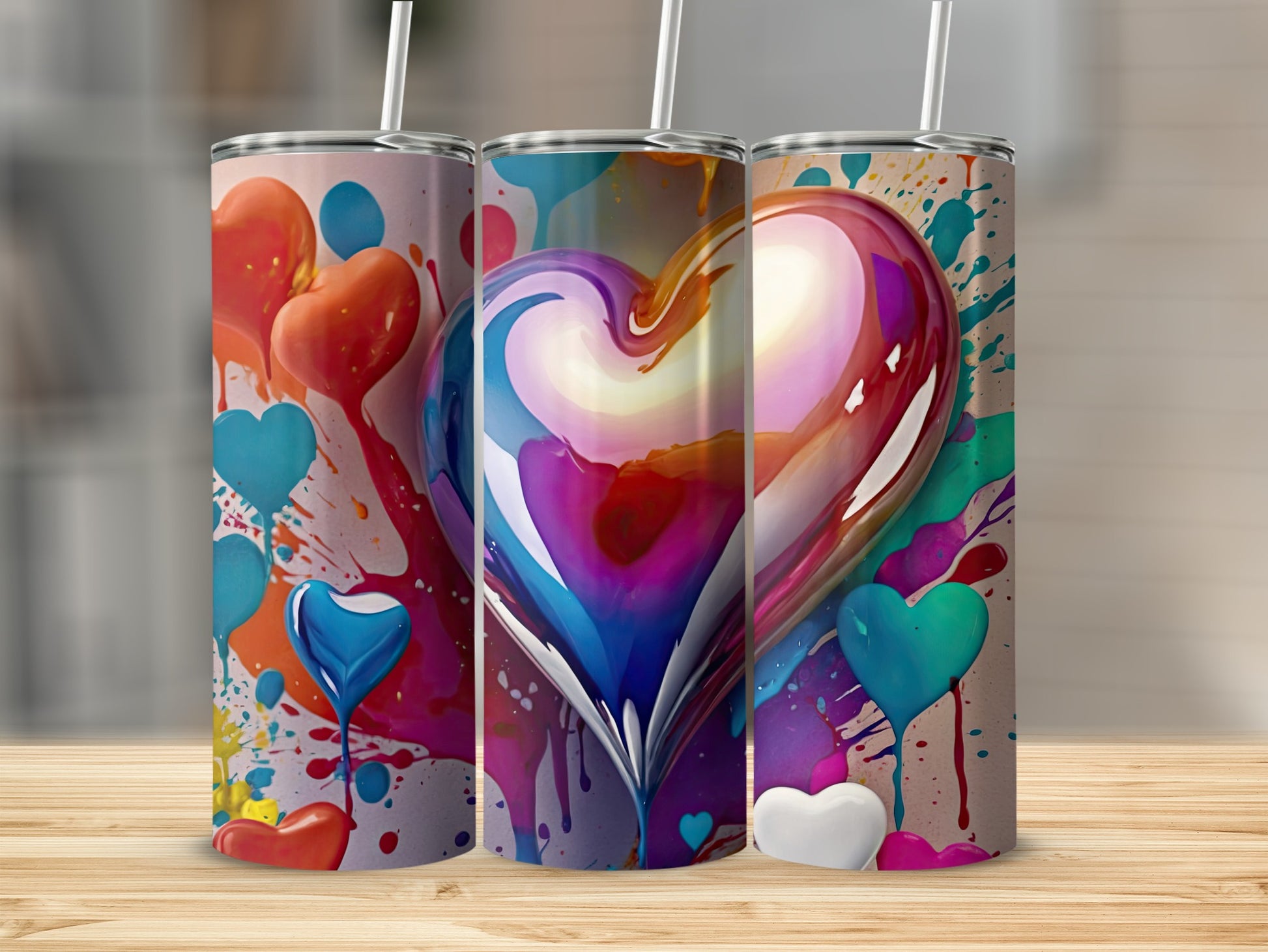 Three tumblers with heart designs and colorful paint splatters.