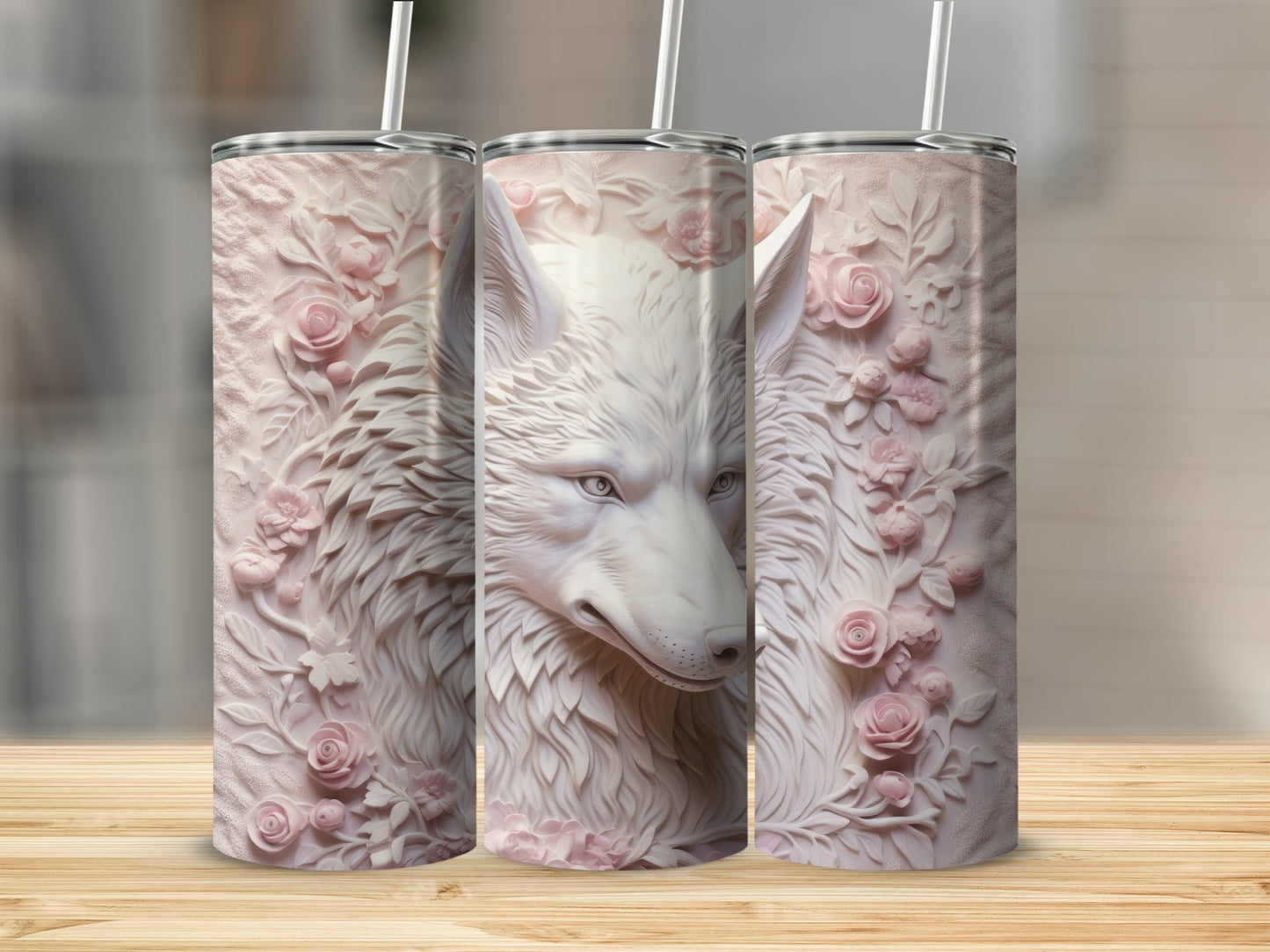 Three pink floral embossed tumblers with a wolf design on a wooden surface.