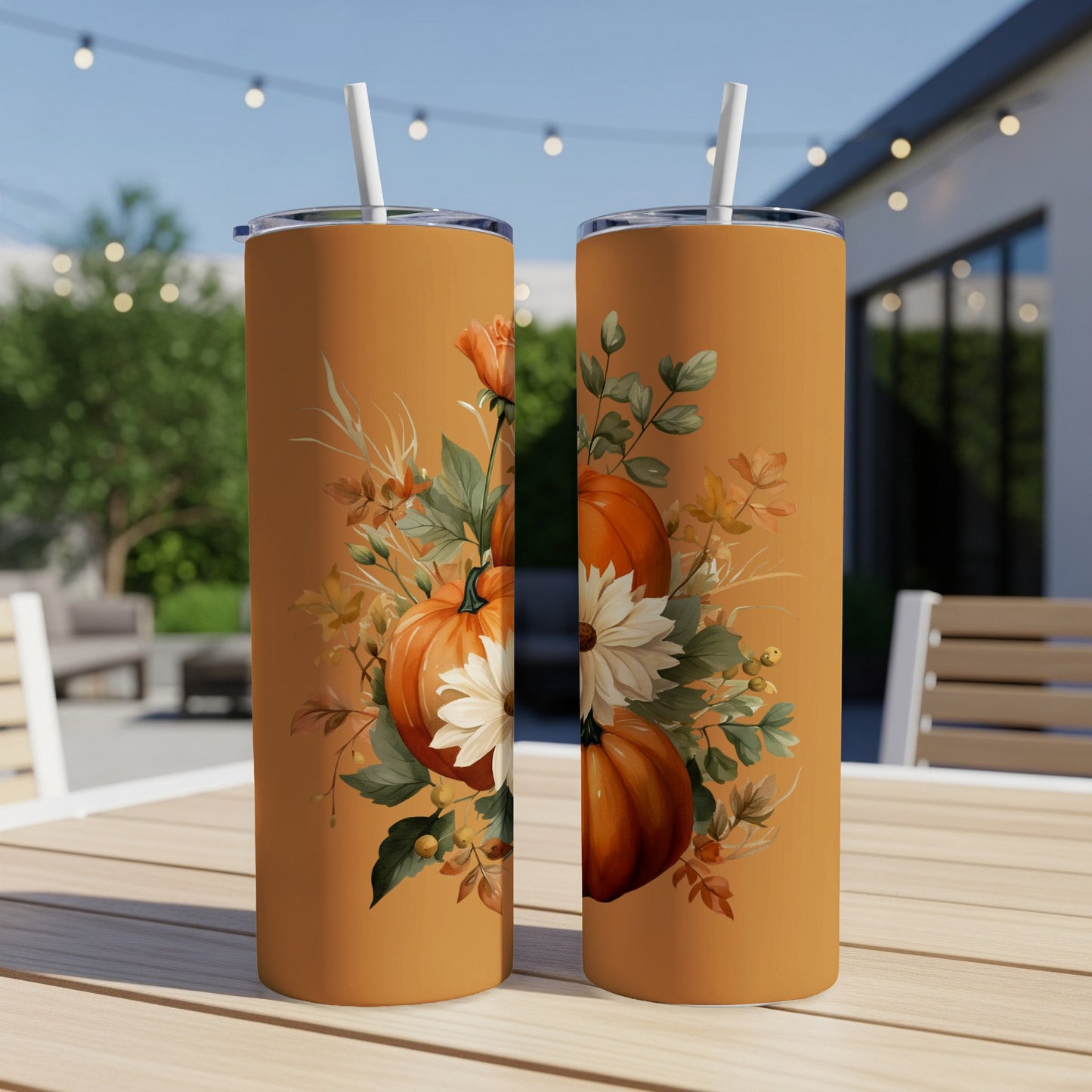 Two tumblers with a pumpkin and floral design sit on a table outdoors.