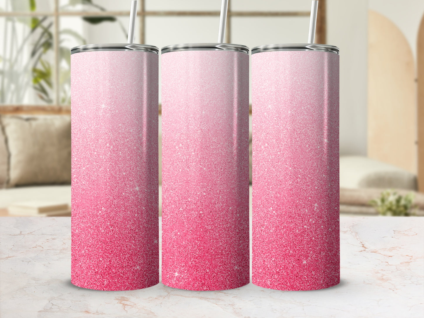 Three pink glitter gradient tumblers with straws on a marble surface.