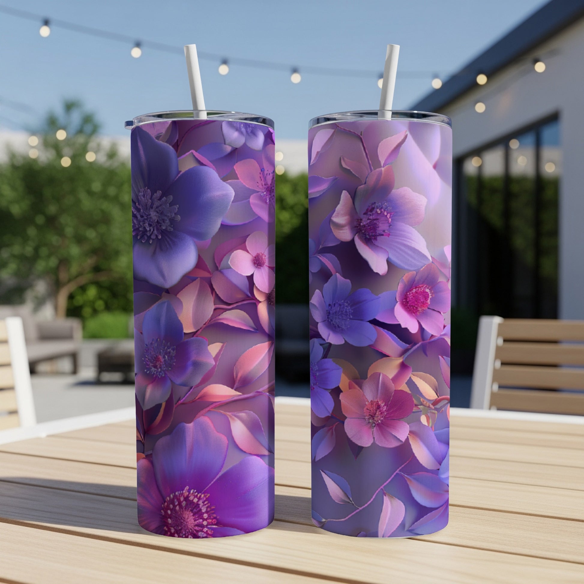 Two purple floral tumblers with straws on a wooden table outdoors.