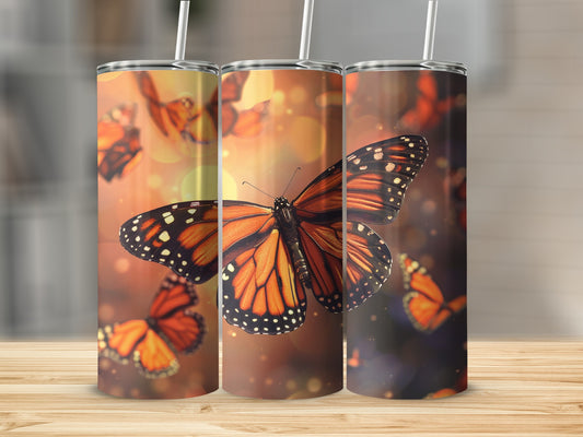 Three tumblers with monarch butterflies against a warm, bokeh background.