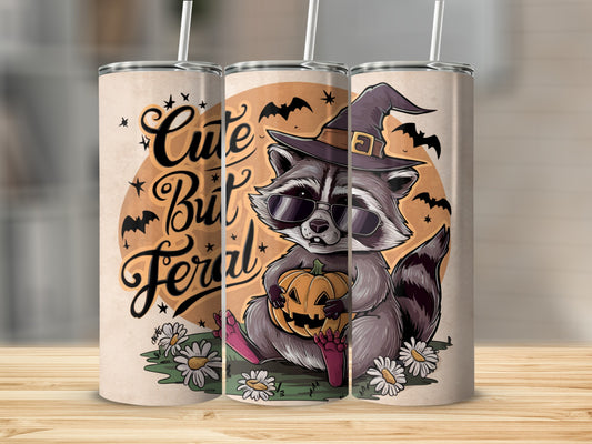 Raccoon in witch hat and sunglasses holds pumpkin with text "Cute But Feral".