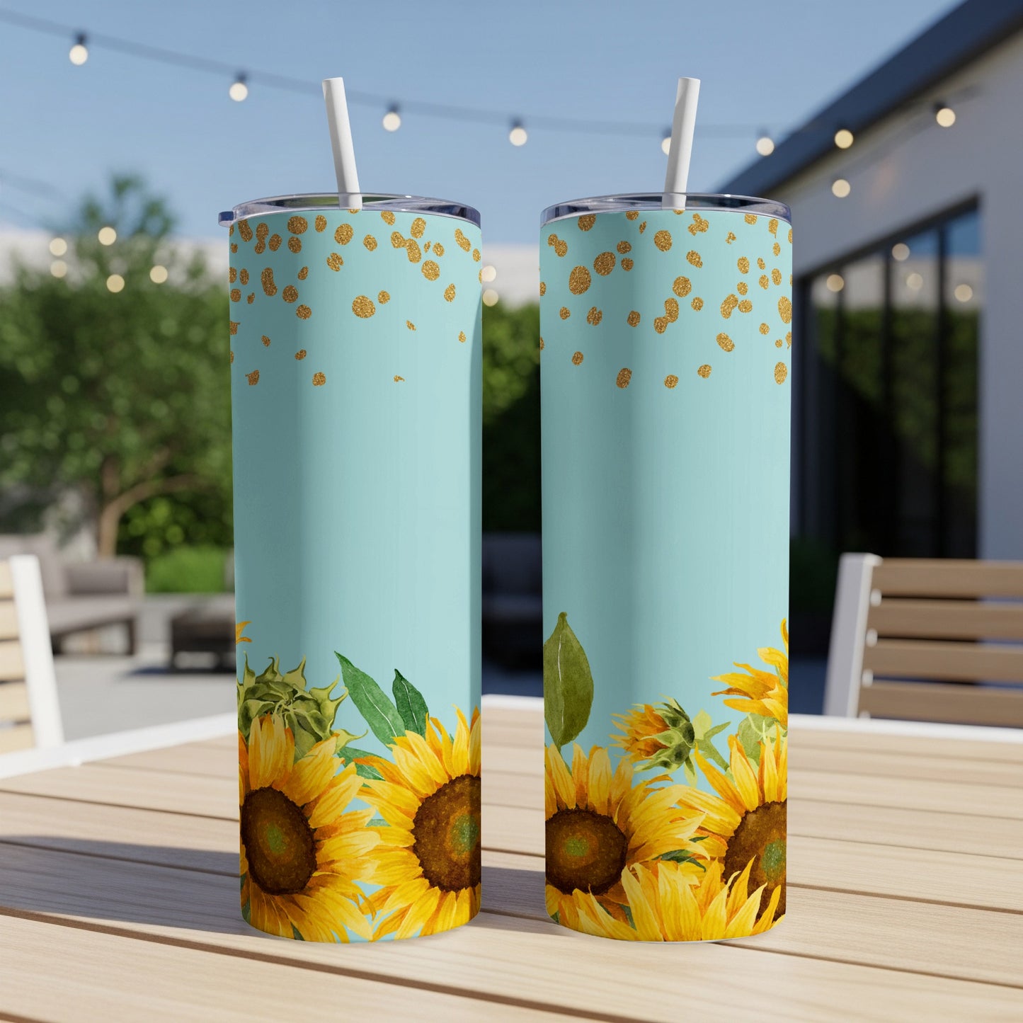 Two teal tumblers with sunflowers and gold glitter accents on outdoor table.