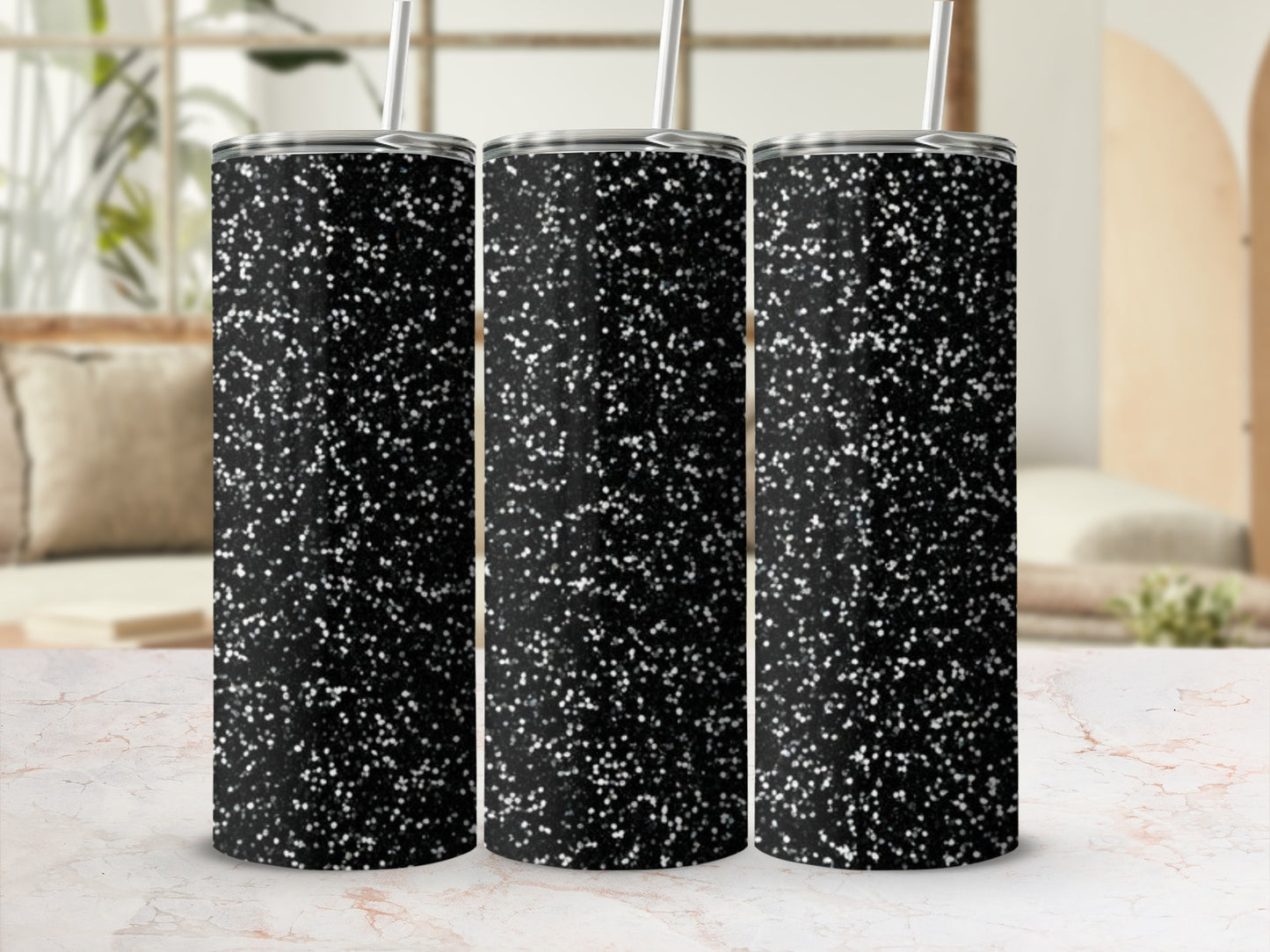 Three black glitter tumblers with white speckles on a marble surface.