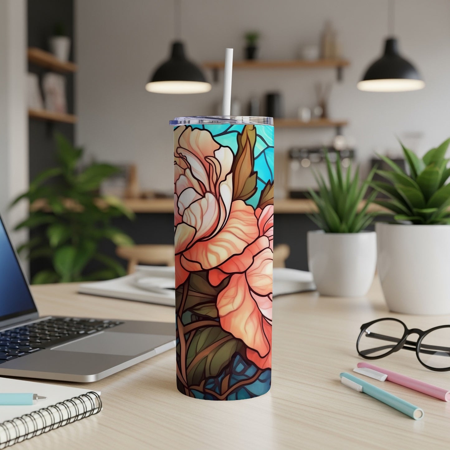 Tall tumbler with stained-glass floral design on a desk.