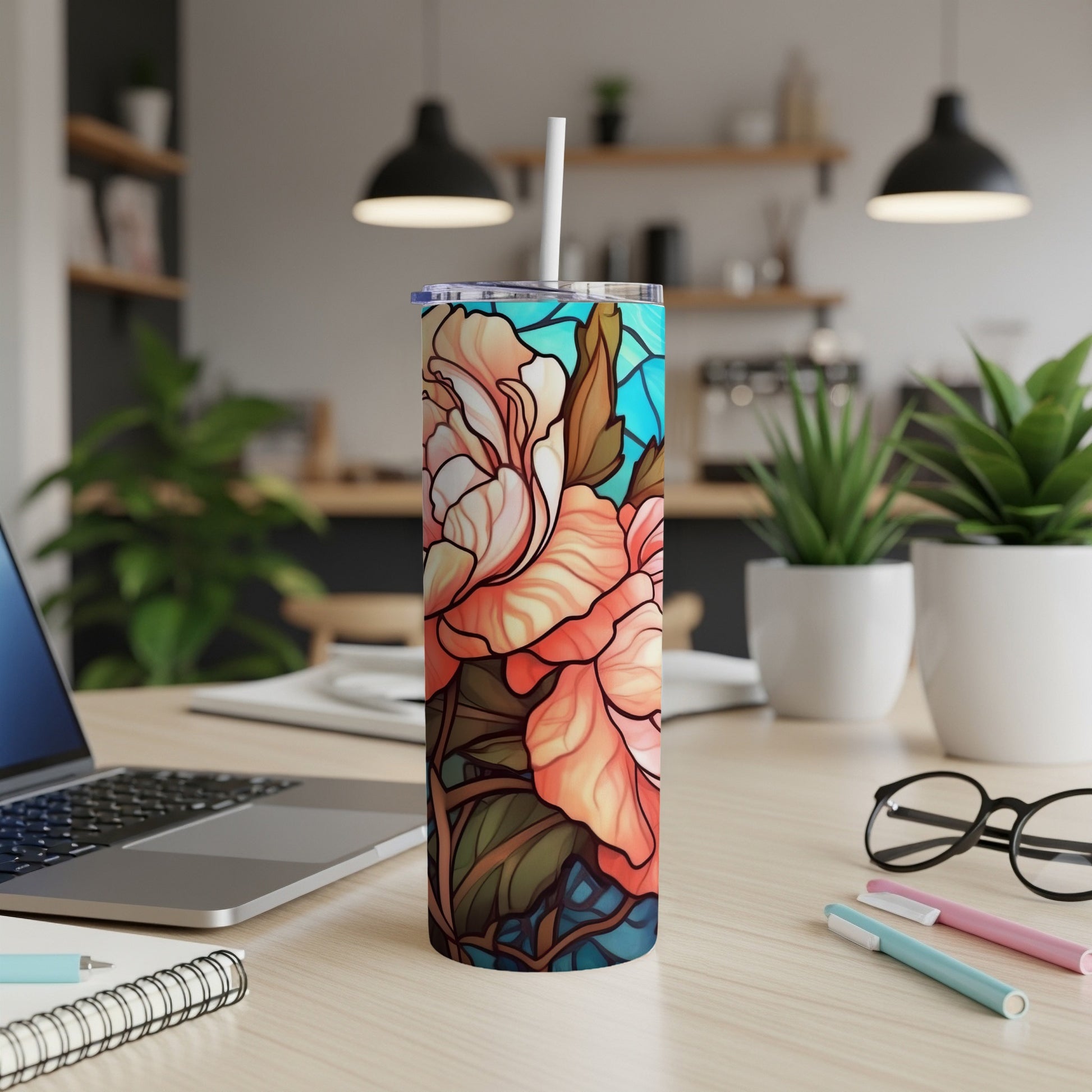 Tall tumbler with stained-glass floral design on a desk.