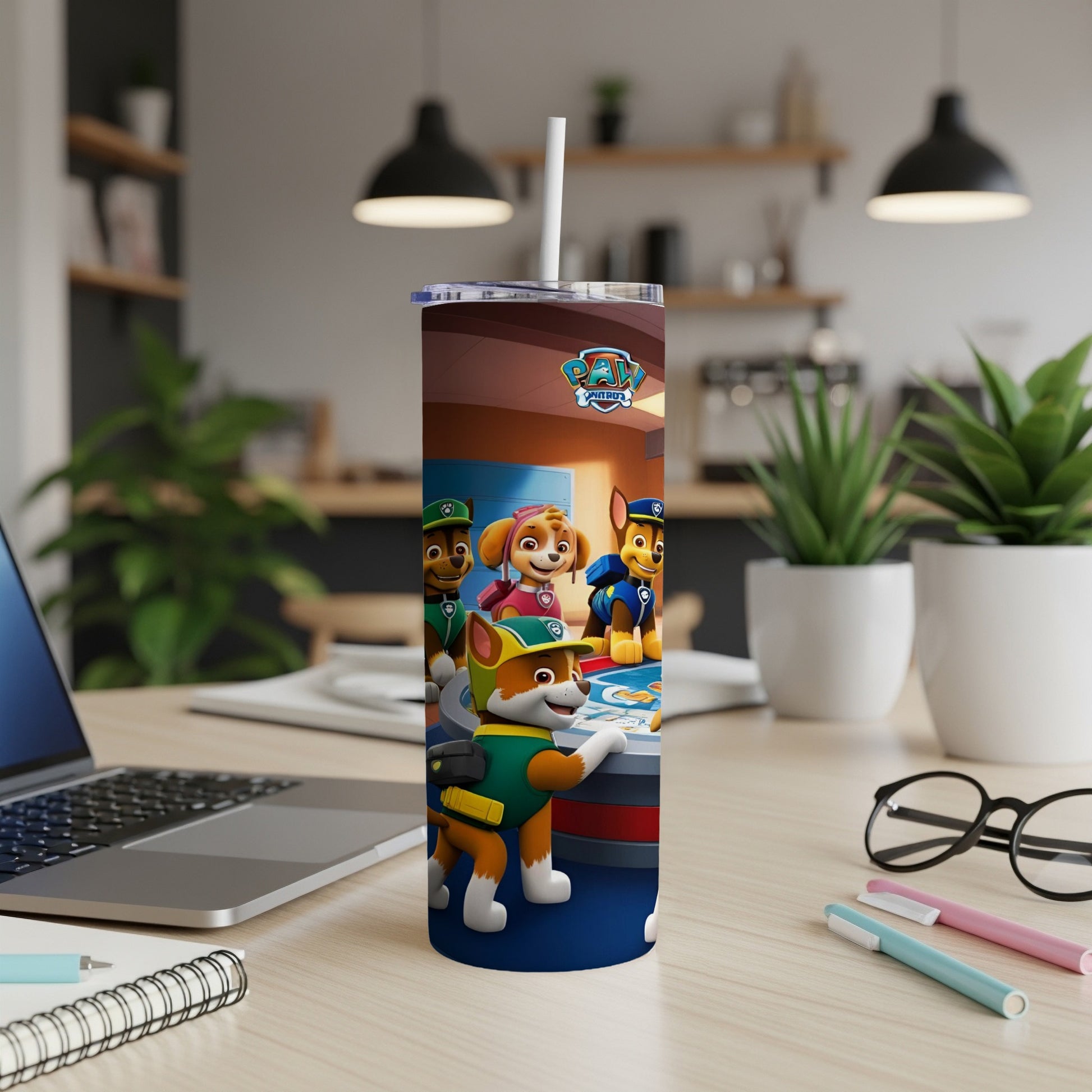 Paw Patrol characters on a blue tumbler with a straw in a home office setting.
