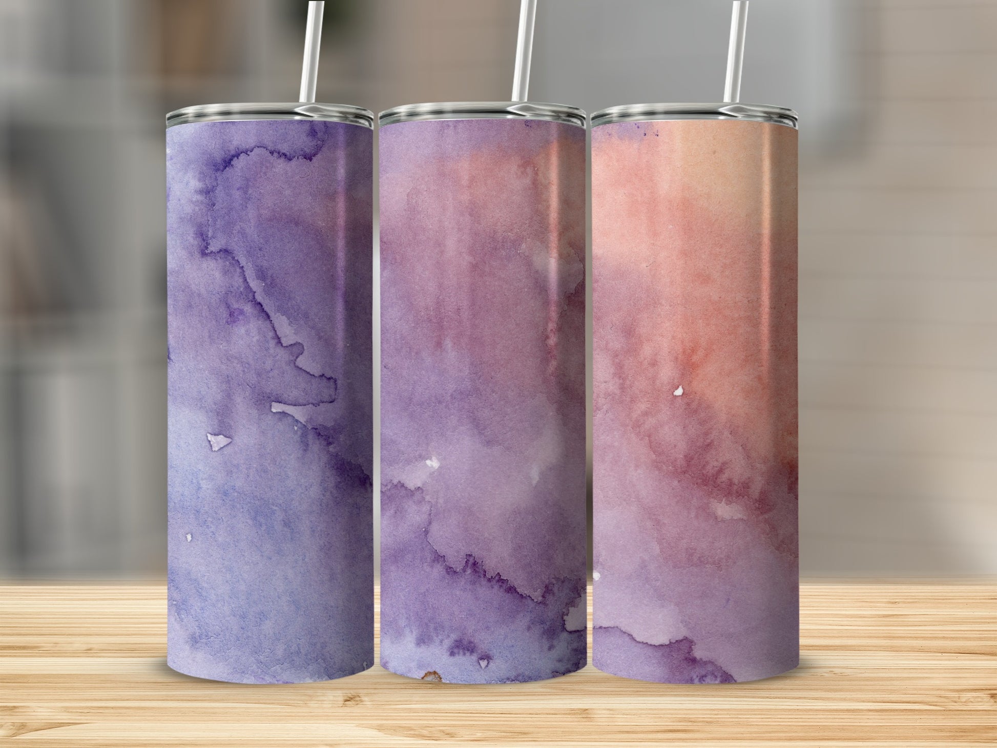 Three tumblers with watercolor designs in purple and pink hues.