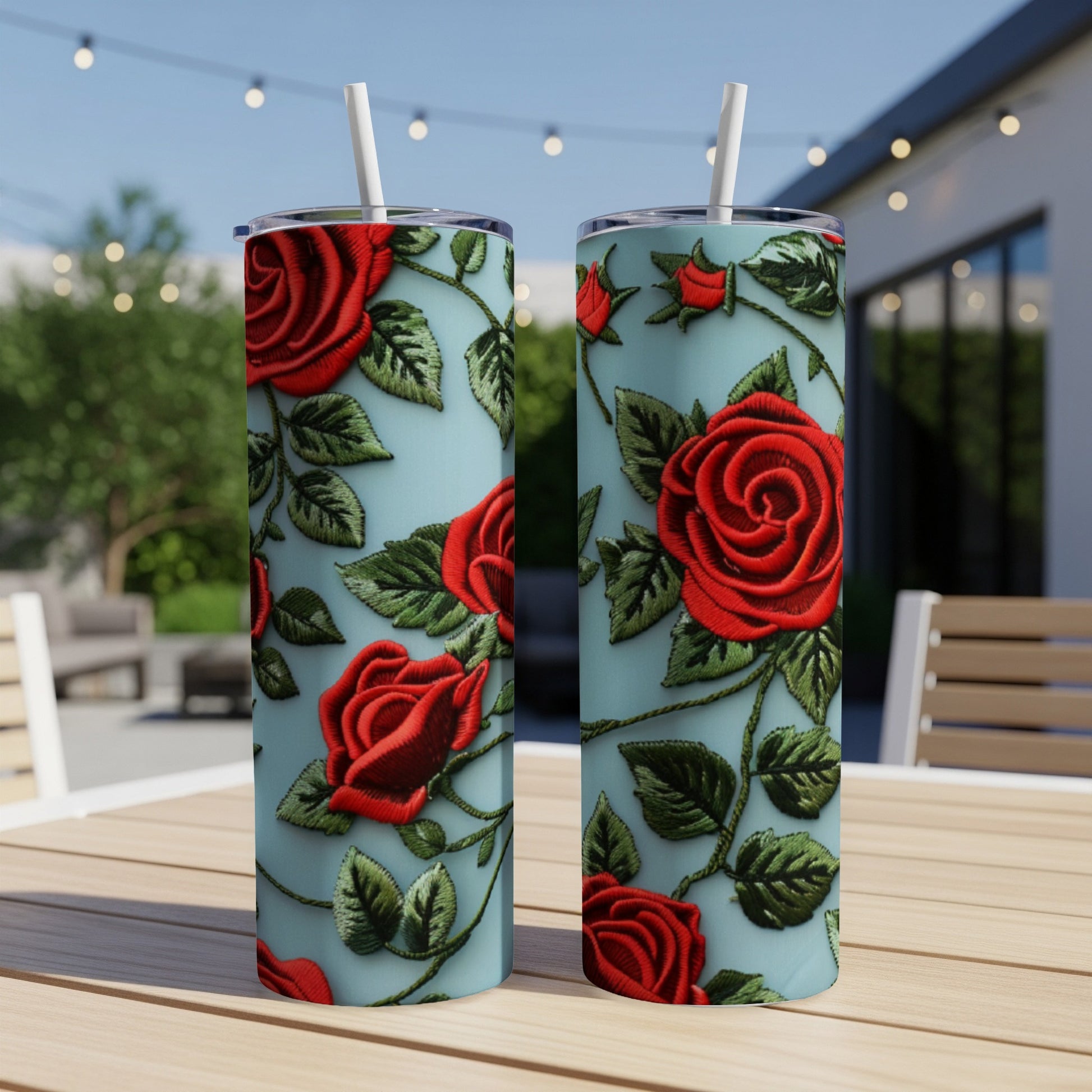 Two blue tumblers with red embroidered roses and green leaves pattern.