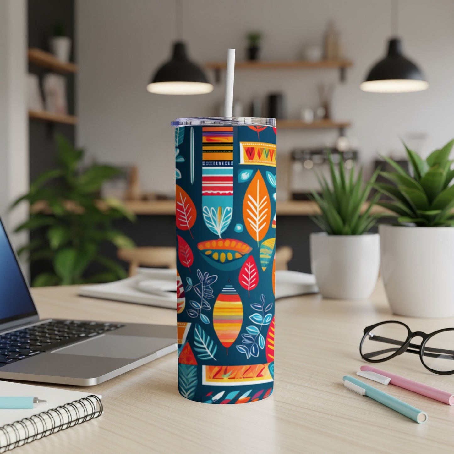 Tumbler with colorful abstract leaf pattern on wooden desk.