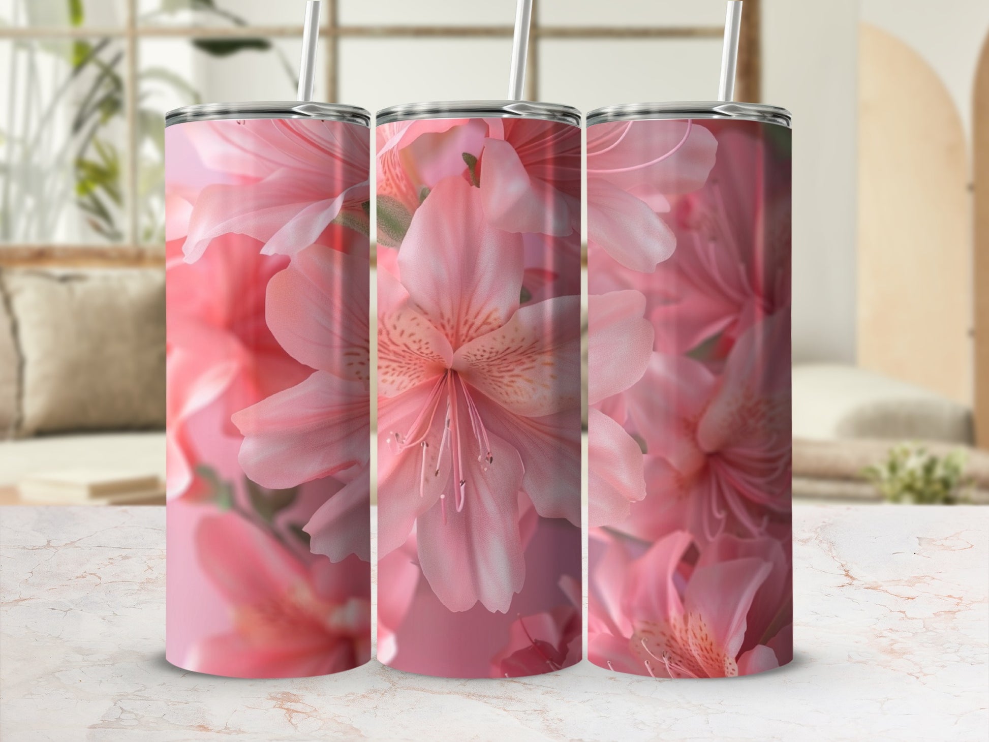 Three pink floral tumblers with straws on a marble surface.