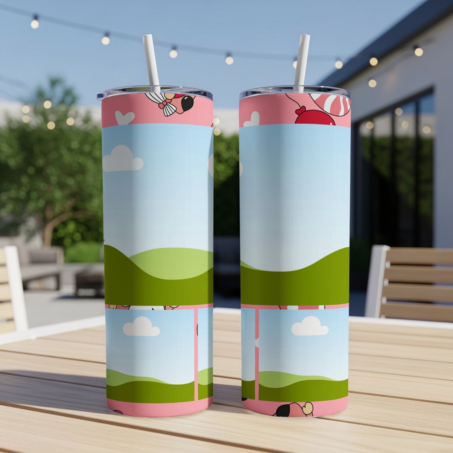 Two tumblers with a cartoon landscape and balloon design sit on a wooden table.