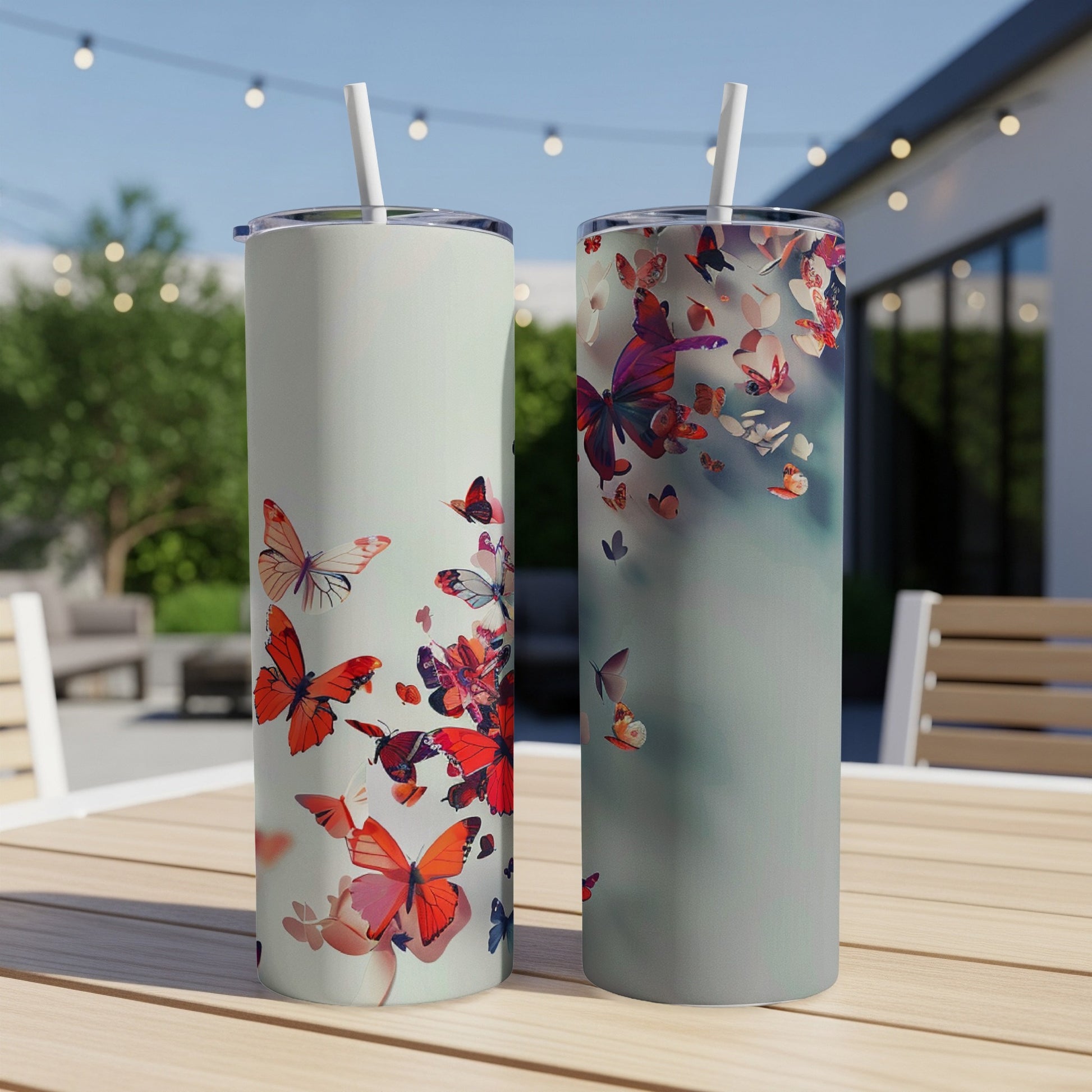 Two tall tumblers with butterfly designs sit on a table.