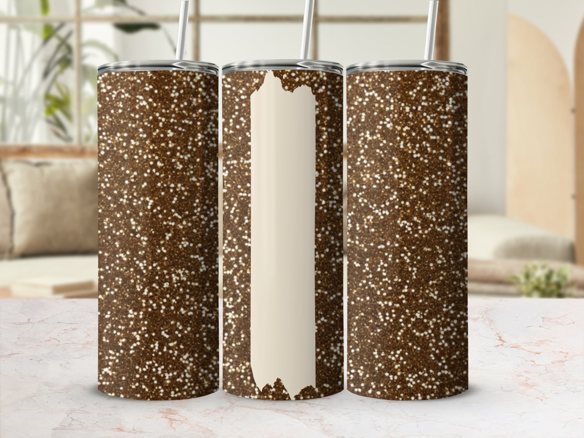 Three glitter tumblers, one with a blank cream label, on a marbled surface.