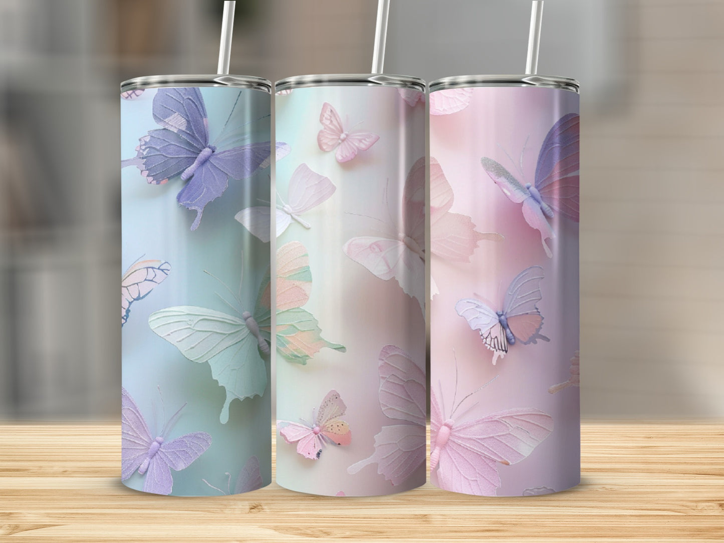 Three pastel butterfly tumblers with straws on a wooden surface.