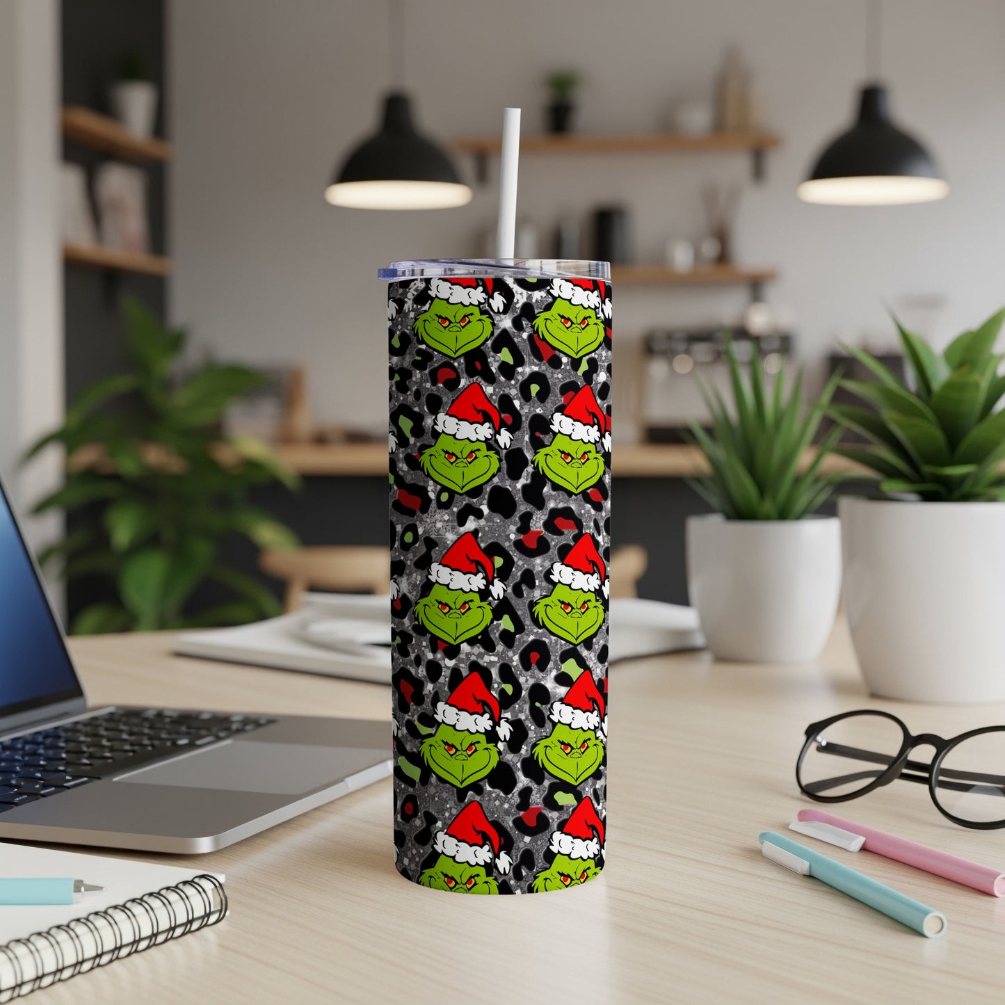Grinch pattern tumbler with Santa hats on a desk.