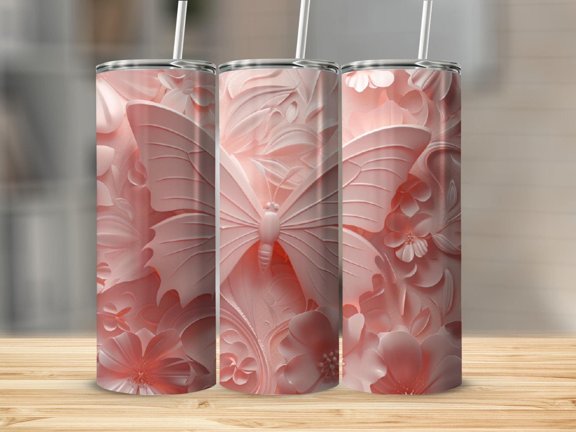Three pink tumblers with embossed butterfly and floral designs on a wooden surface.