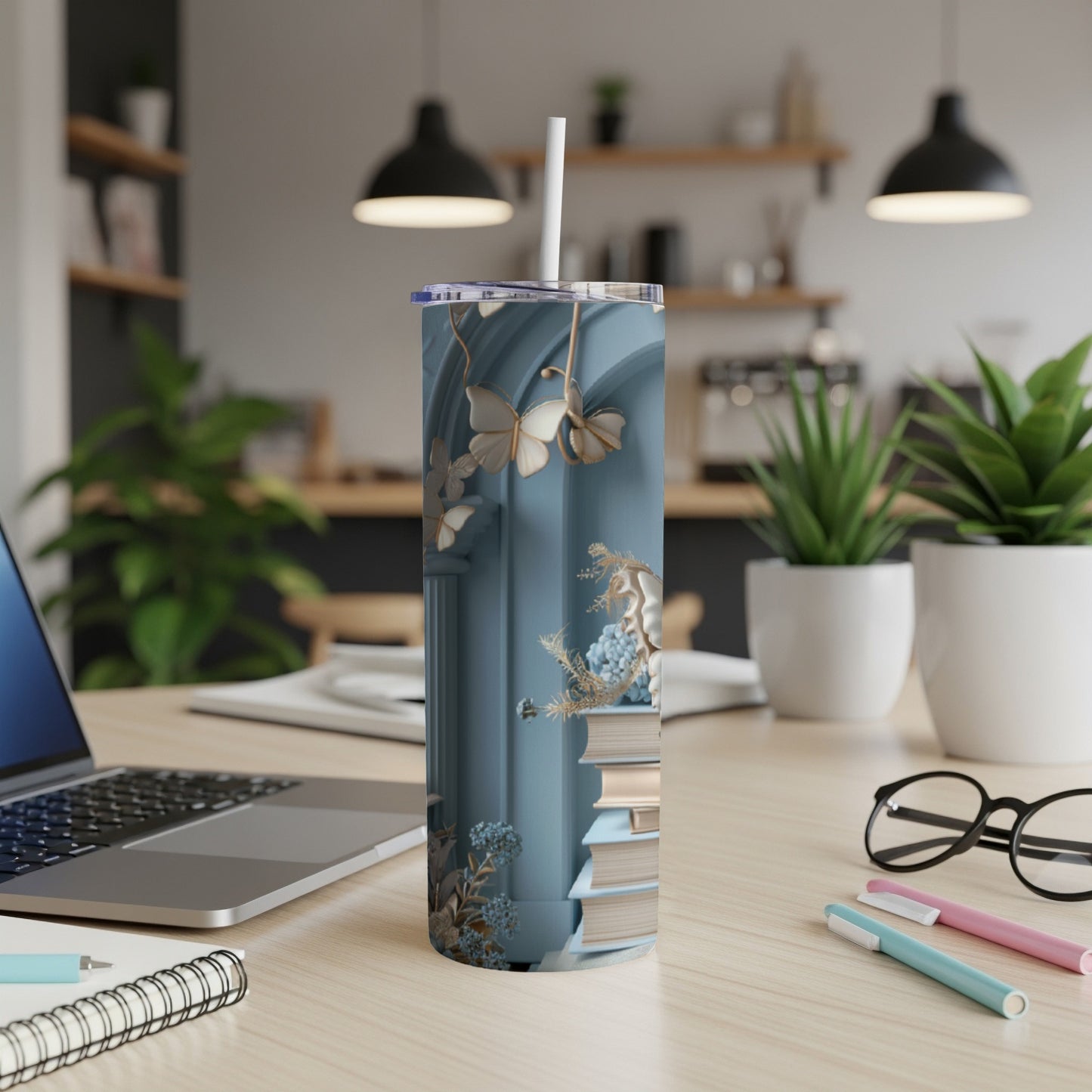 Blue tumbler with ornate details and stacked books.