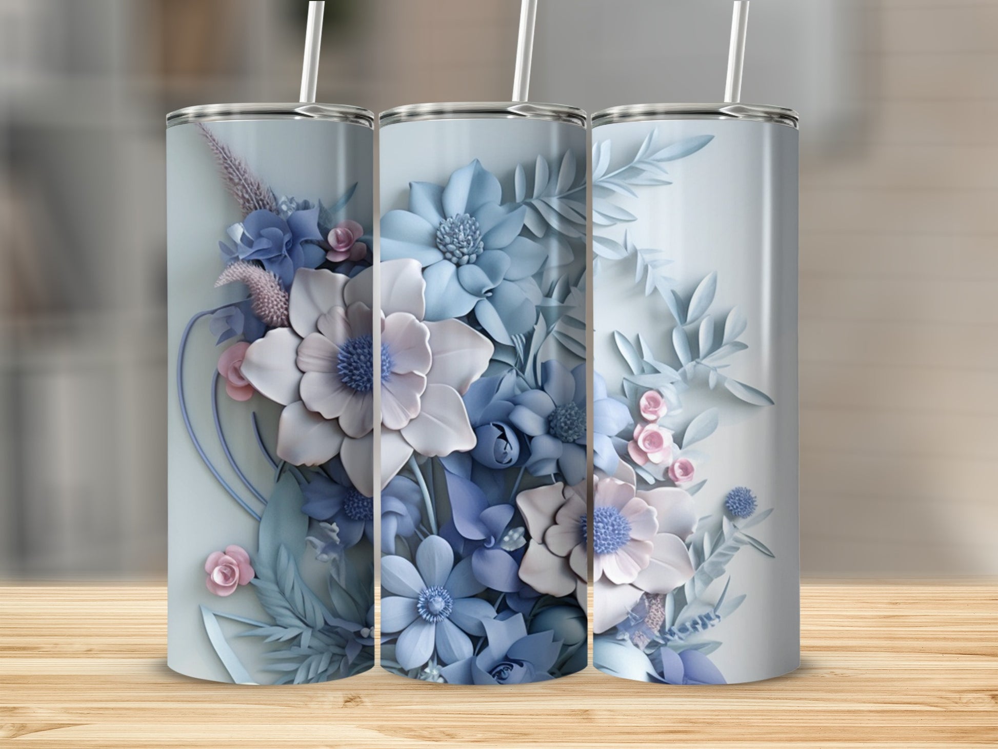 Three tall tumblers with blue and pink floral designs on a wooden surface.