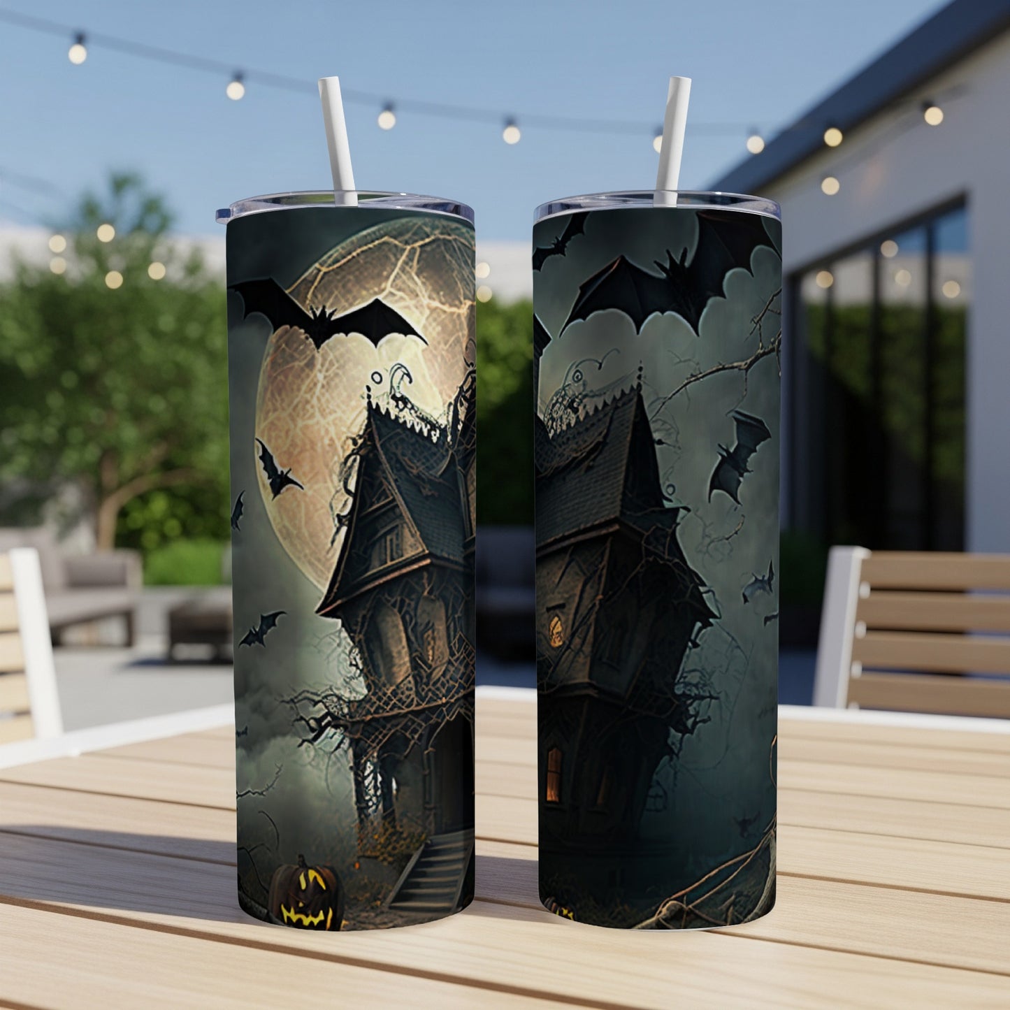 Two tumblers with a spooky haunted house, bats, and jack-o-lanterns against a full moon.
