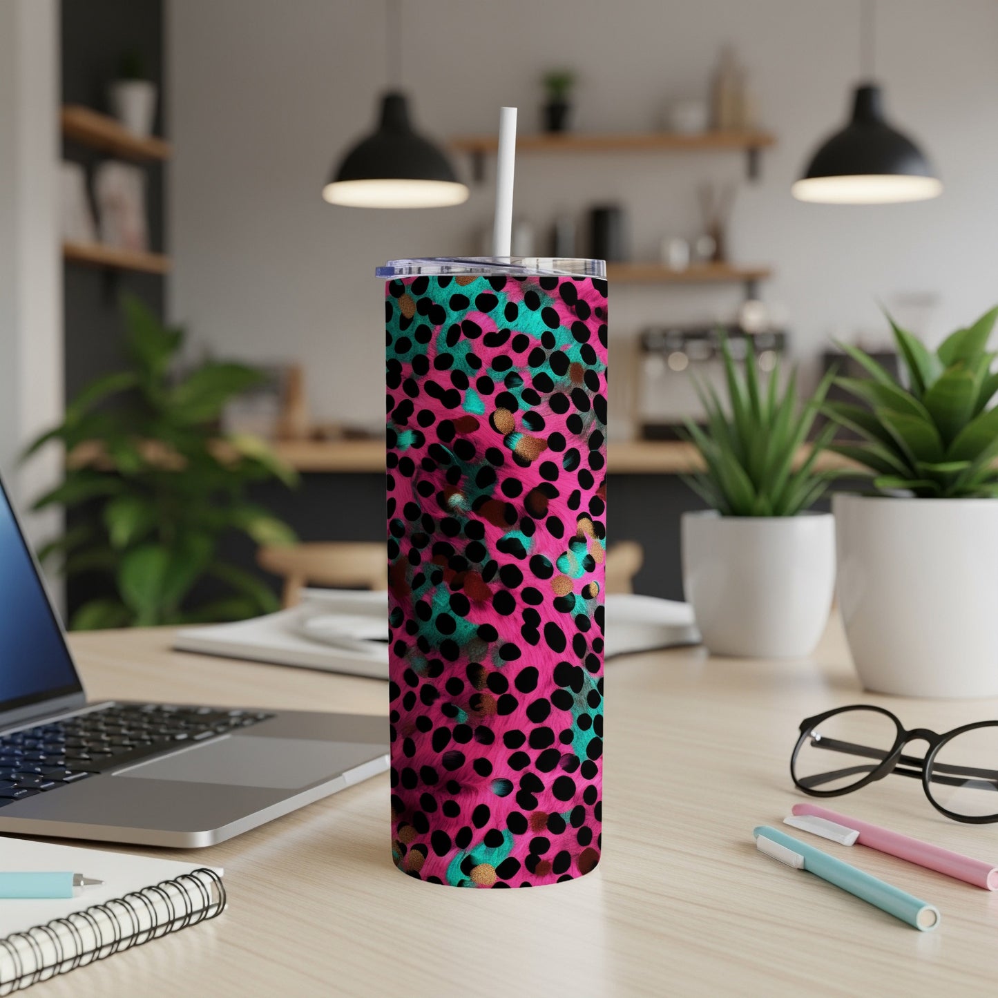 Pink tumbler with teal and gold animal print design on a desk.