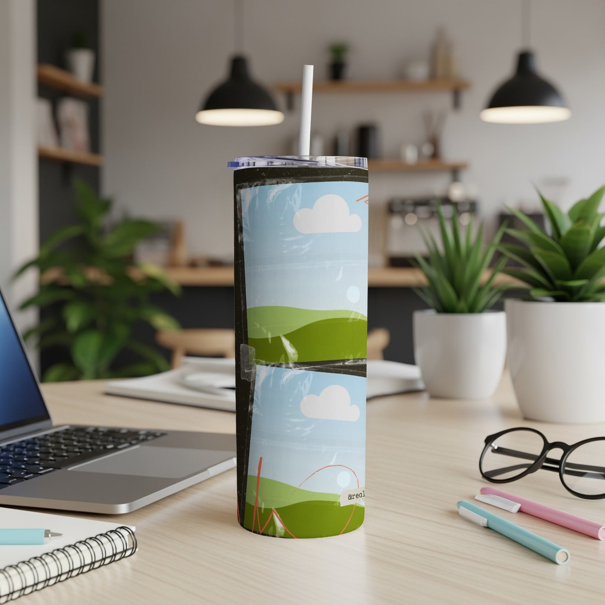 Tumbler with sky and rolling green hills design, a straw inserted.