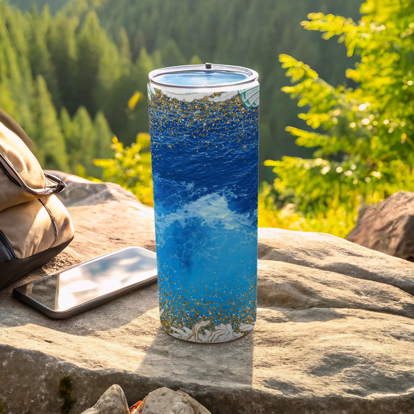 Blue ocean waves and gold glitter on a tumbler with phone and backpack.