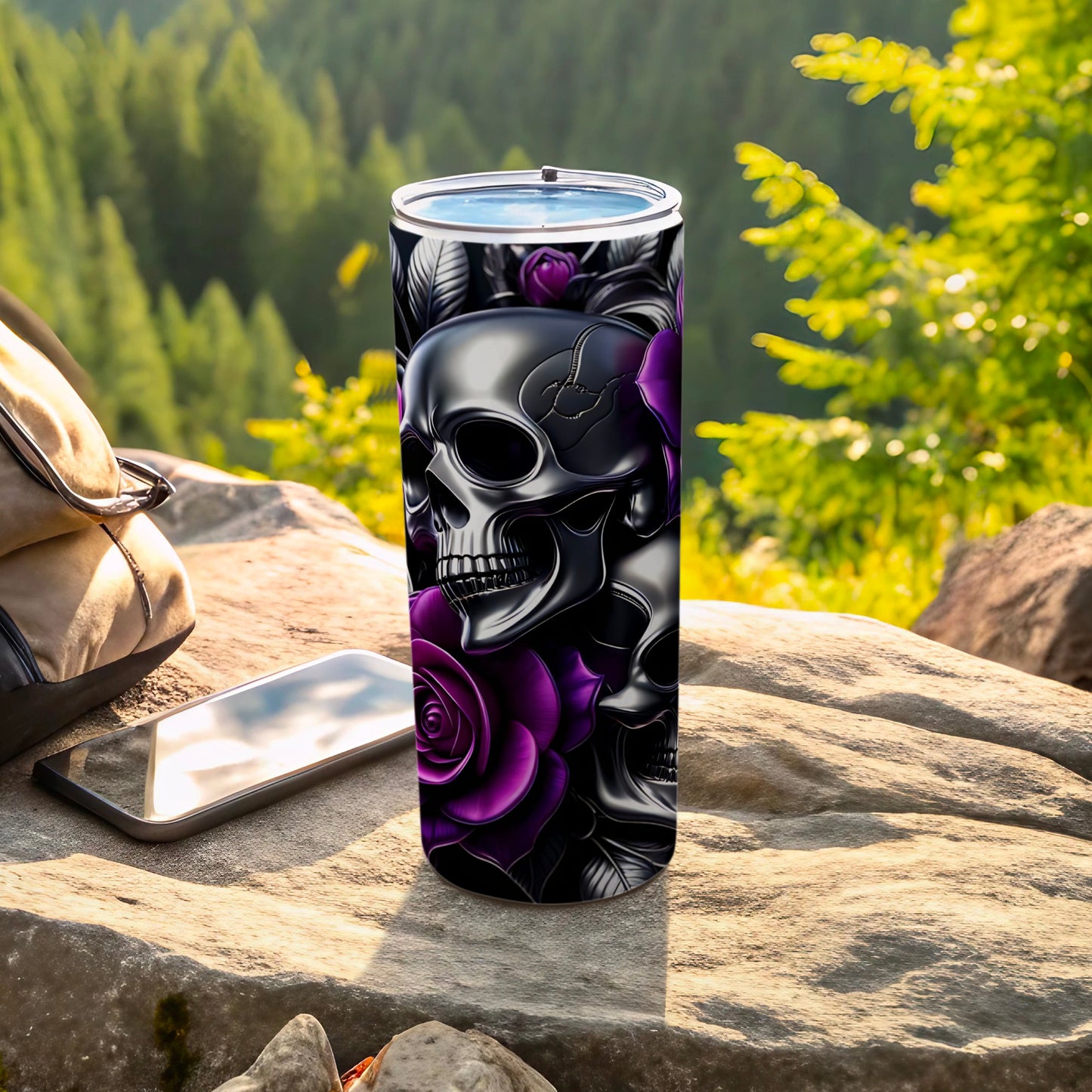 Black tumbler with skulls and purple roses on a rocky surface.