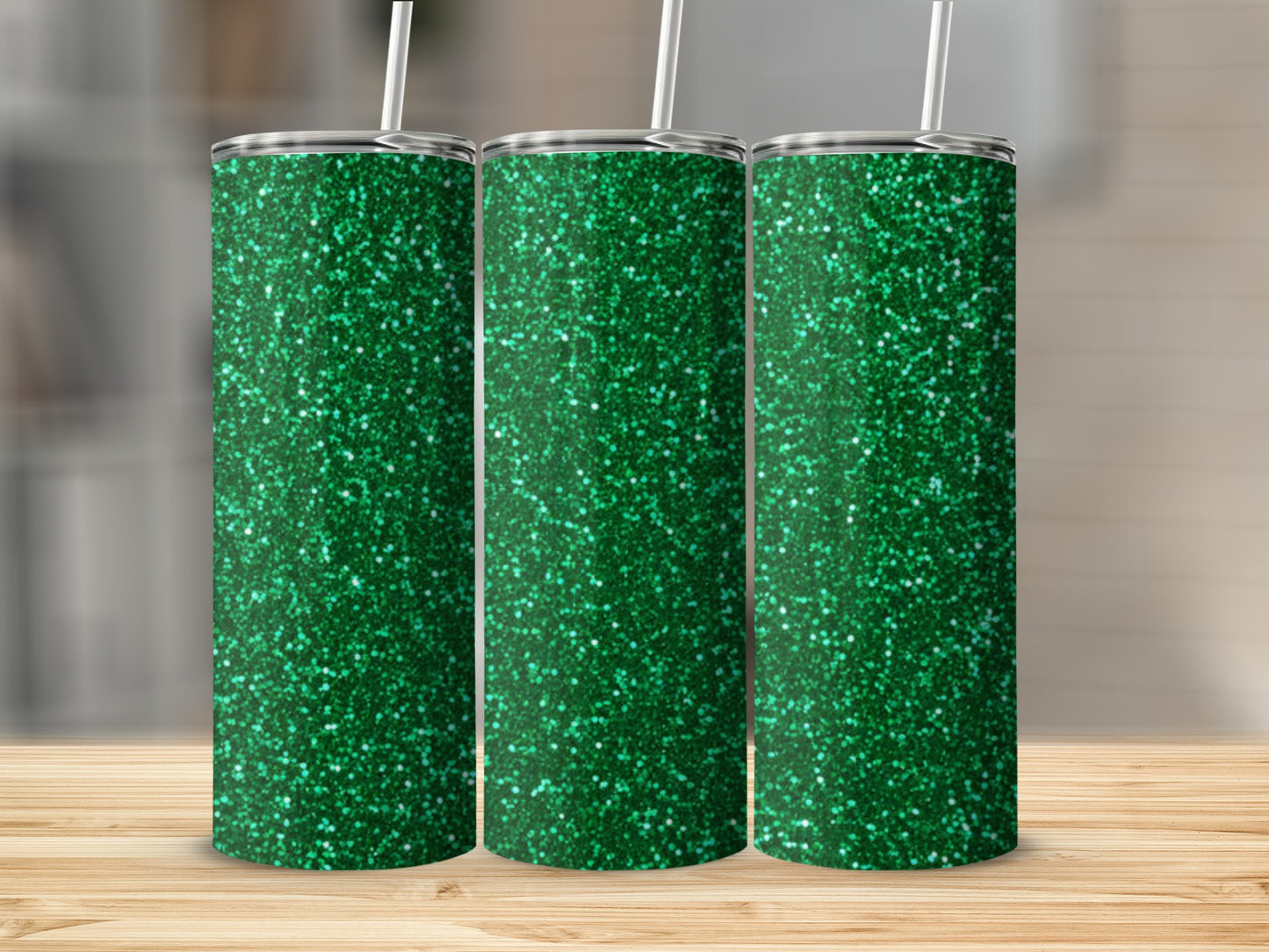 Three green glitter tumblers with white straws on a wooden surface.