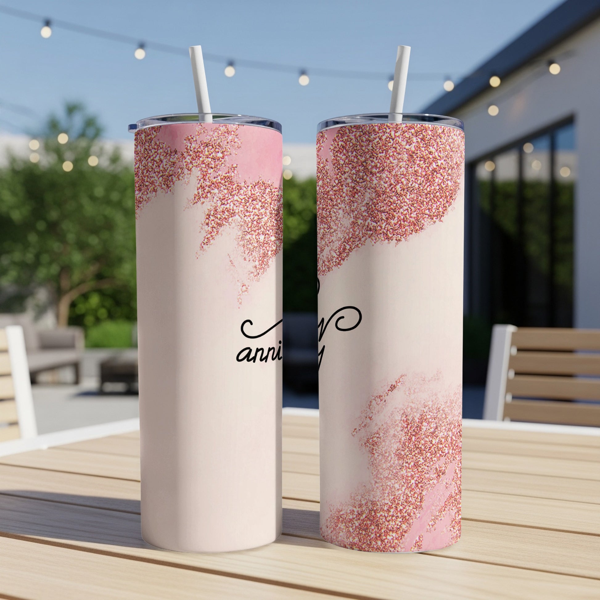 Two pink glitter tumblers on a table, decorated with "anniversary".