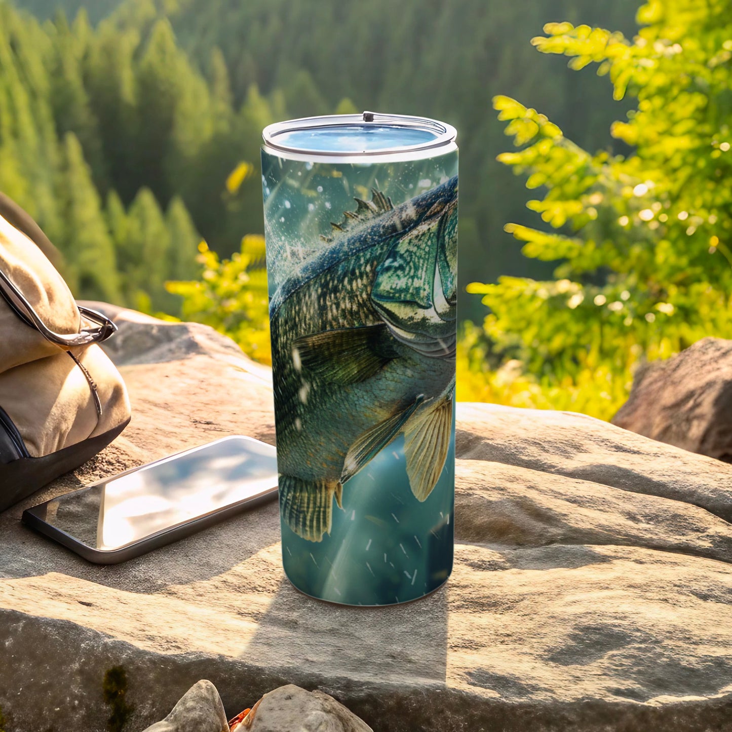 Bass fishing tumbler with water splashes on a rock with backpack and phone.
