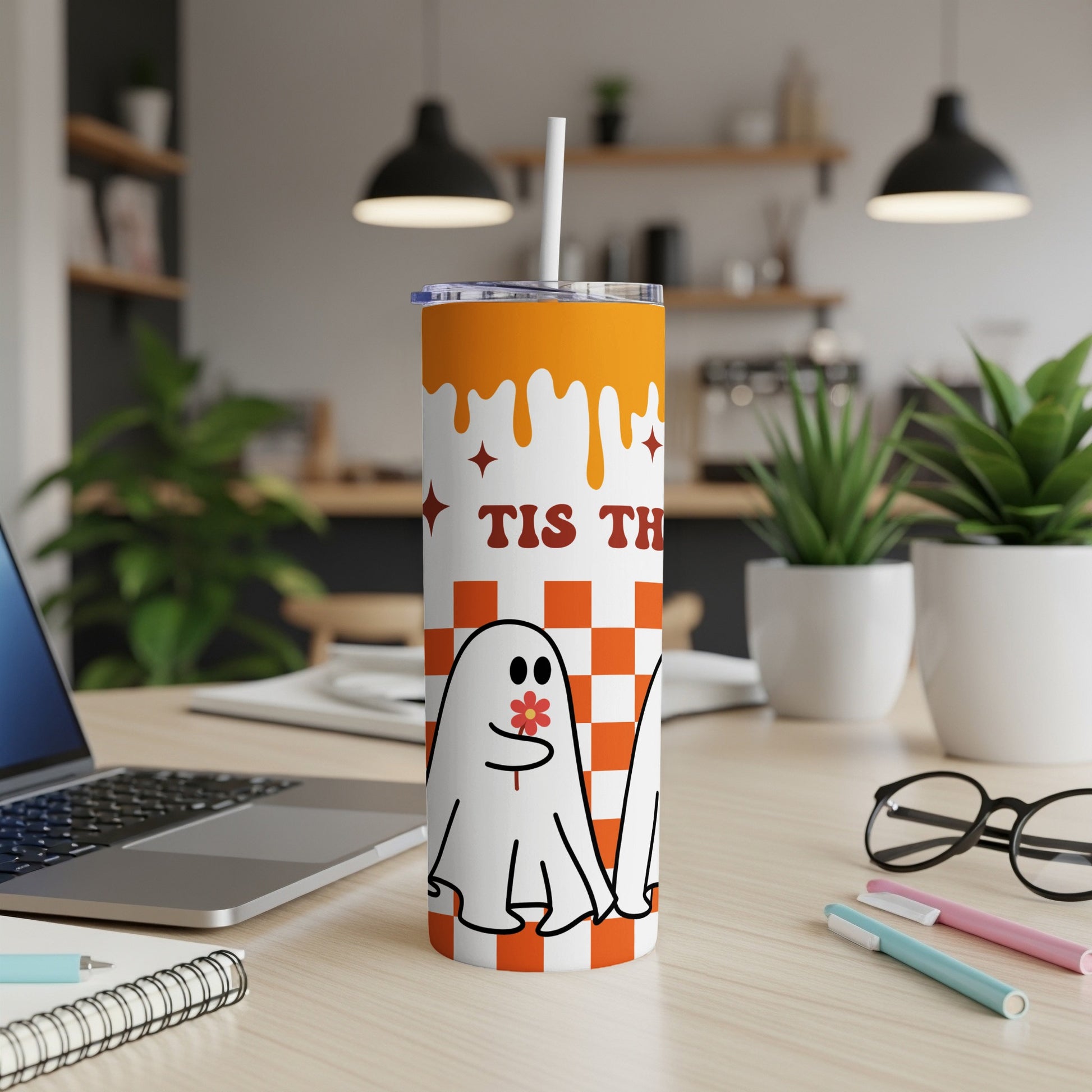 Tumbler with orange drip design, ghost, and "Tis The" text on checkered background.