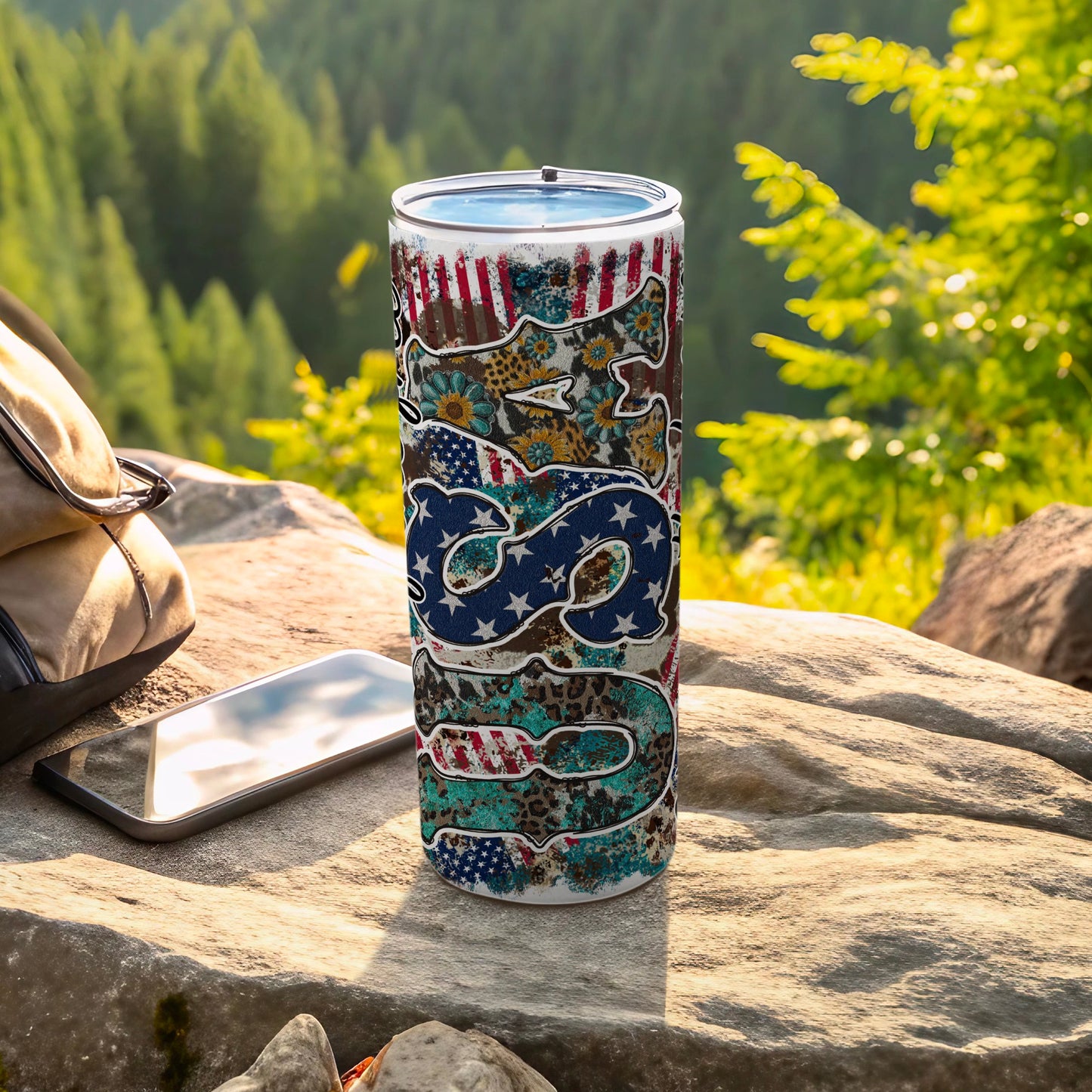 Patriotic USA flag and animal print tumbler on a rock outdoors.
