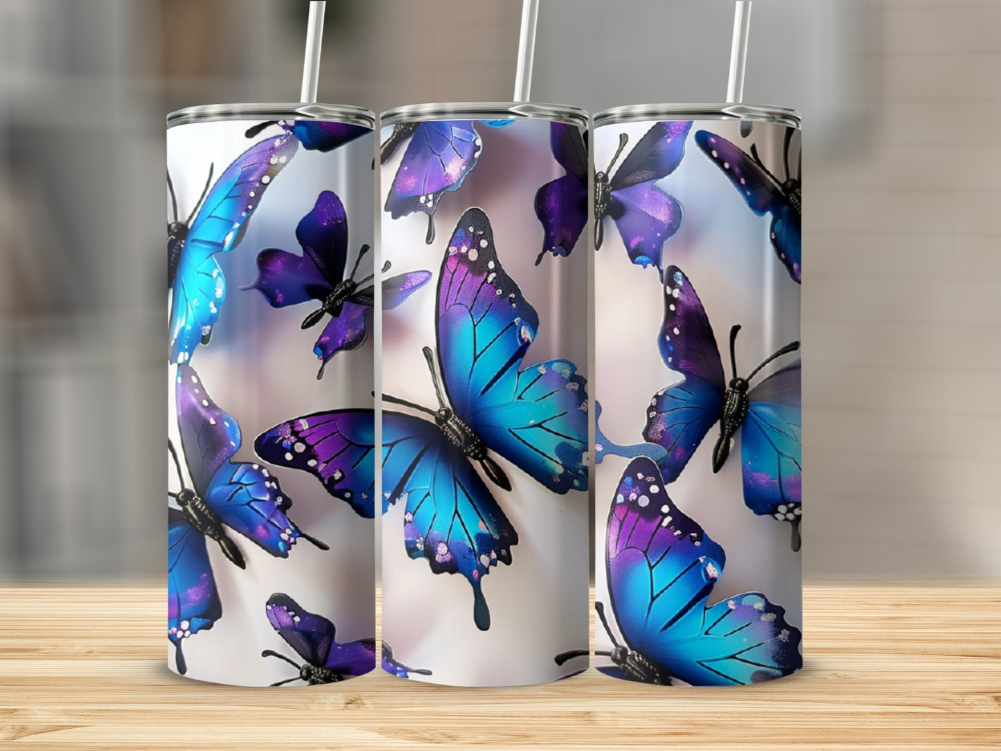 Three tumblers with colorful butterfly designs and straws.